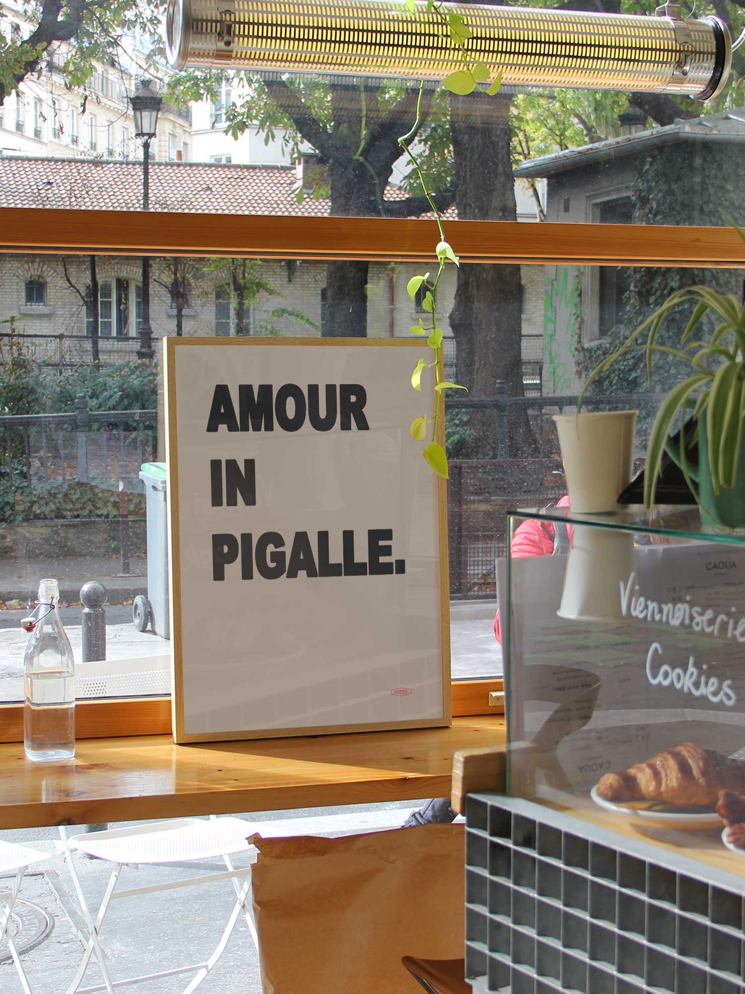 Affiche Amour In Pigalle de Haritz dans un coffee shop parisien branché et lumineux avec vue sur rue.