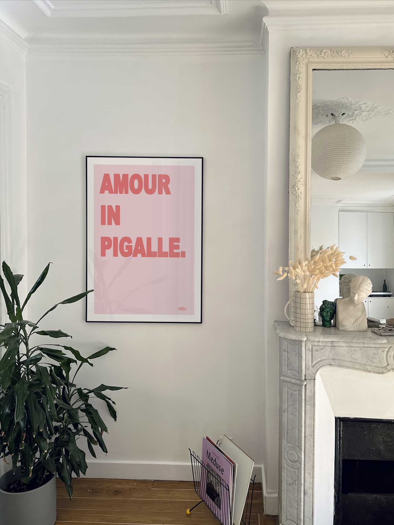 Affiche Amour in Pigalle de Haritz accrochée au mur près d'une cheminée en marbre dans un appartement parisien.