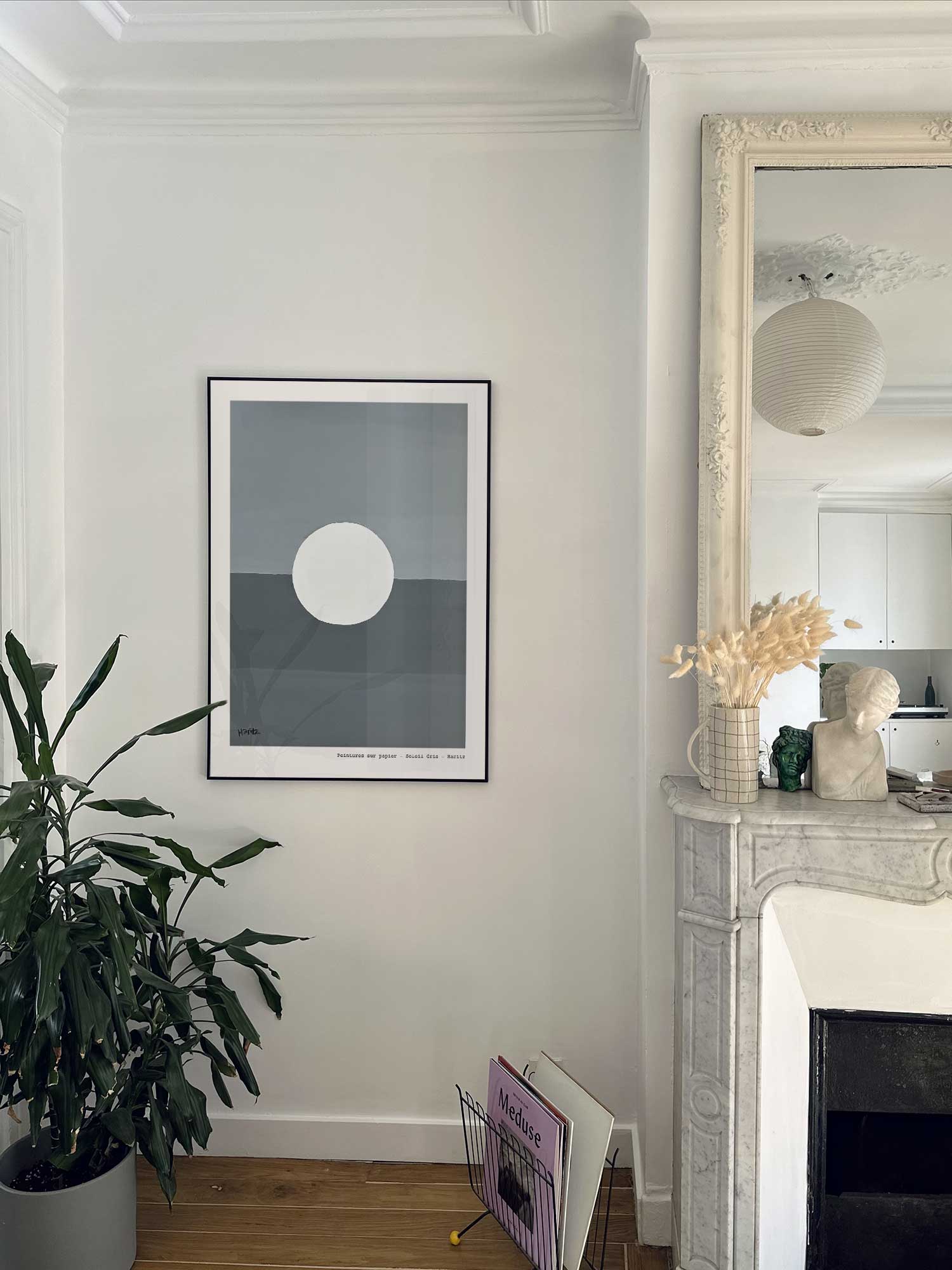 Affiche Lune de Haritz accrochée au mur près d'une cheminée en marbre dans un appartement parisien.