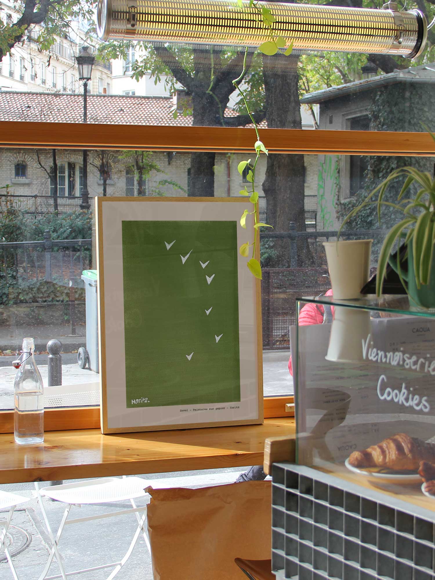 Affiche Envol de Haritz dans un coffee shop parisien lumineux et branché avec vue sur rue.