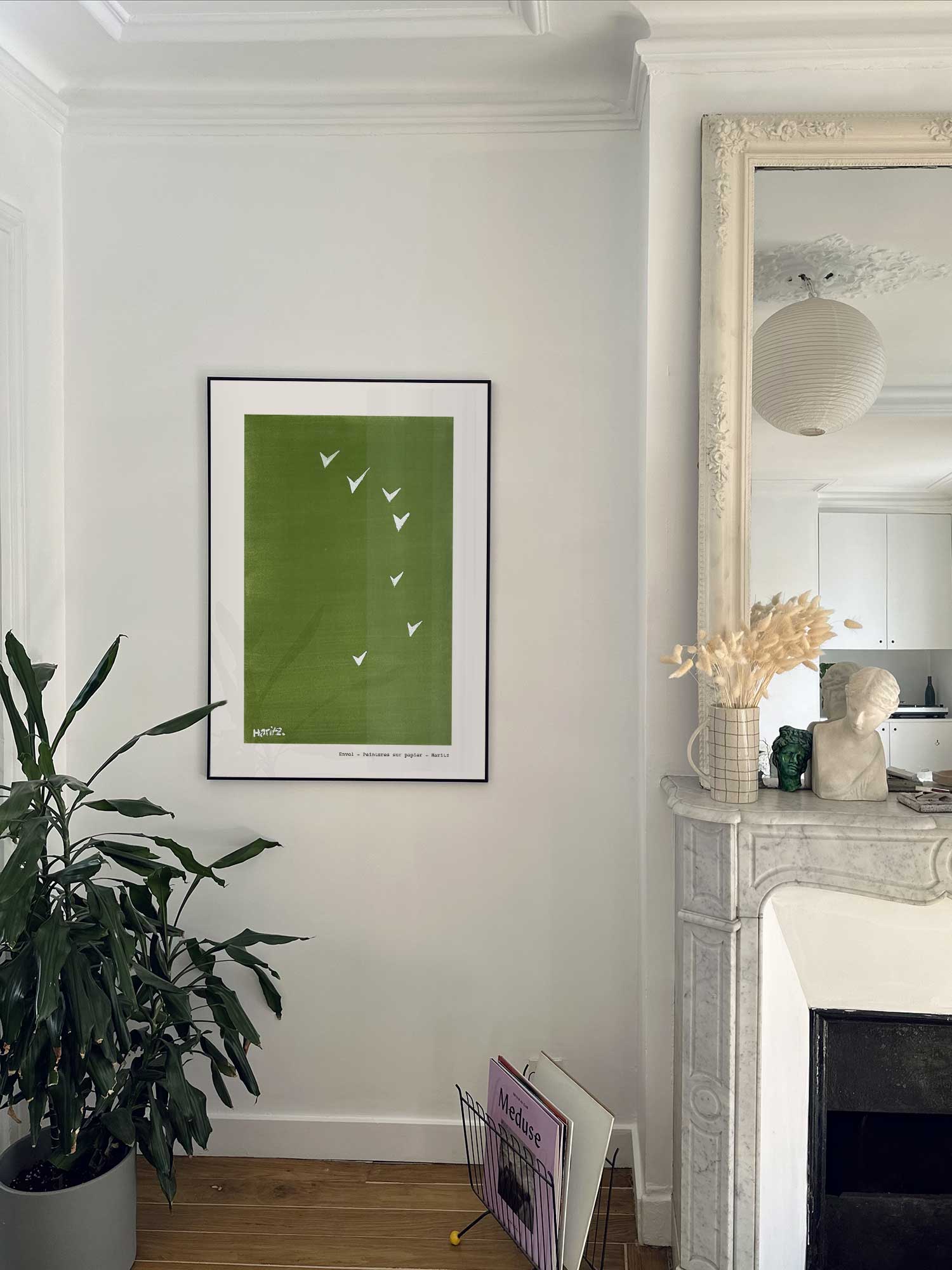 Affiche Envol de Haritz accrochée au mur près d'une cheminée en marbre dans un appartement parisien.