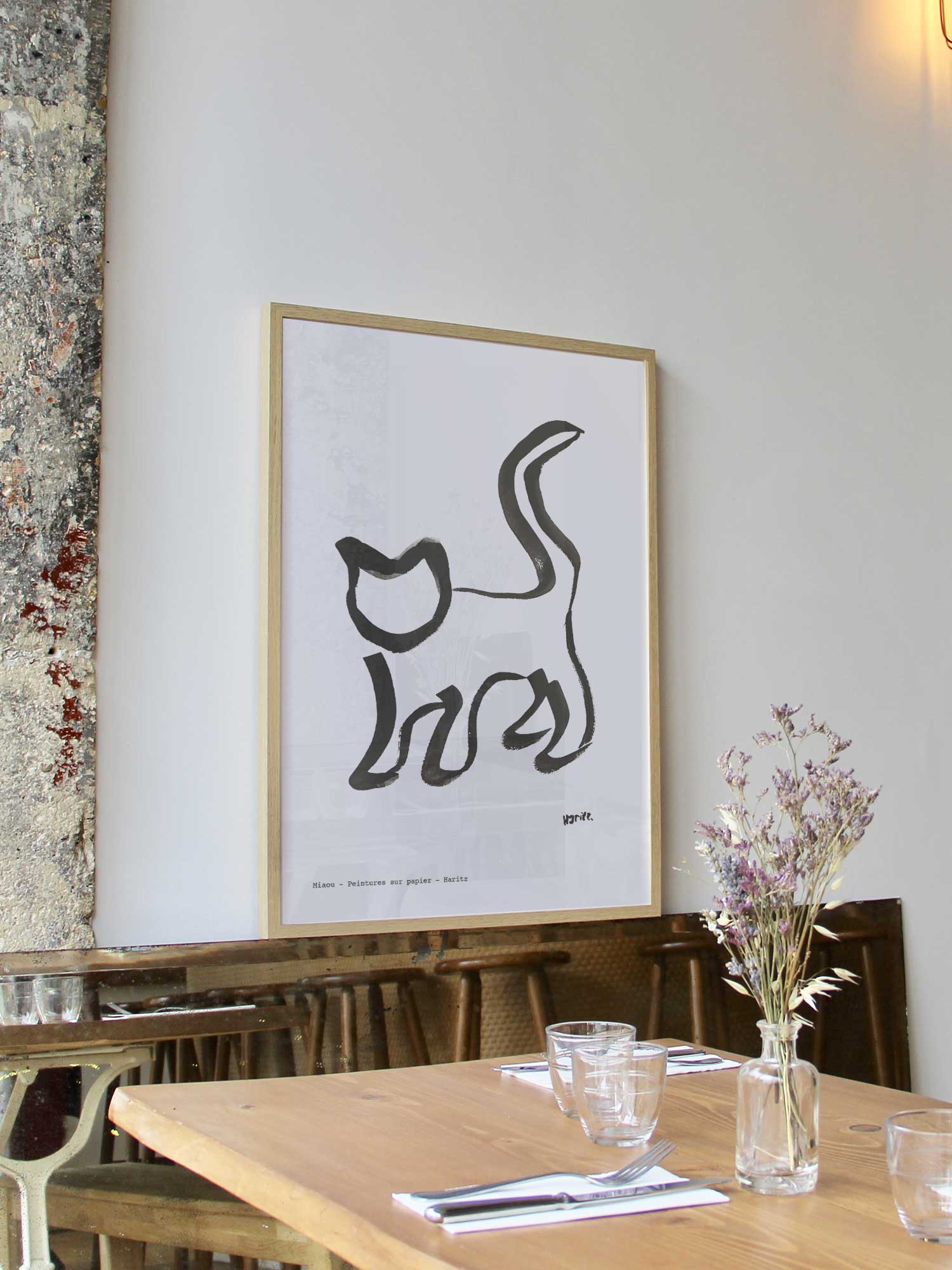 Affiche Miaou de Haritz encadrée dans un restaurant bistrot parisien au style minimaliste et branché.