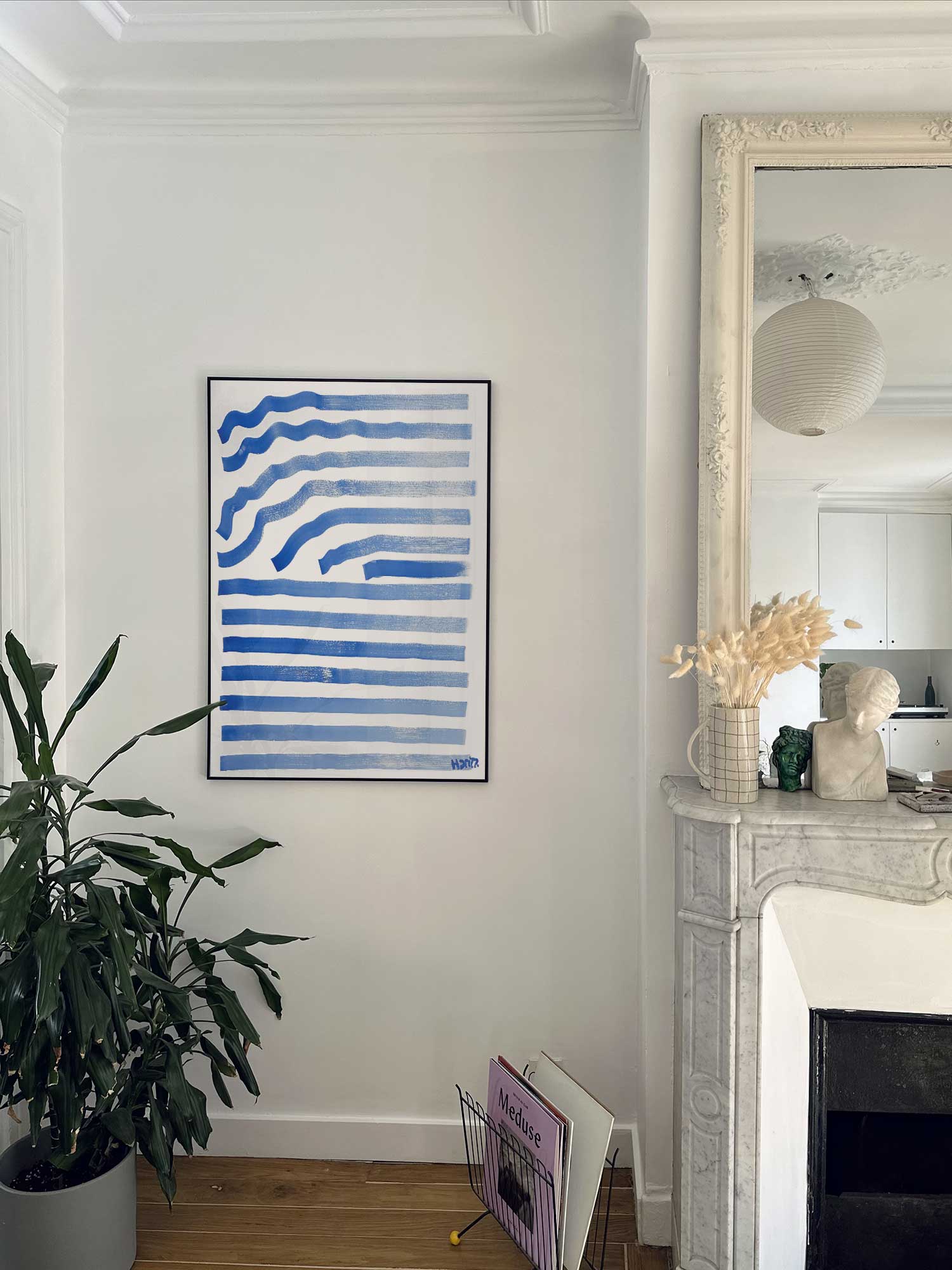 Affiche Ondes bleues de Haritz accrochée au mur près d'une cheminée en marbre dans un appartement parisien.