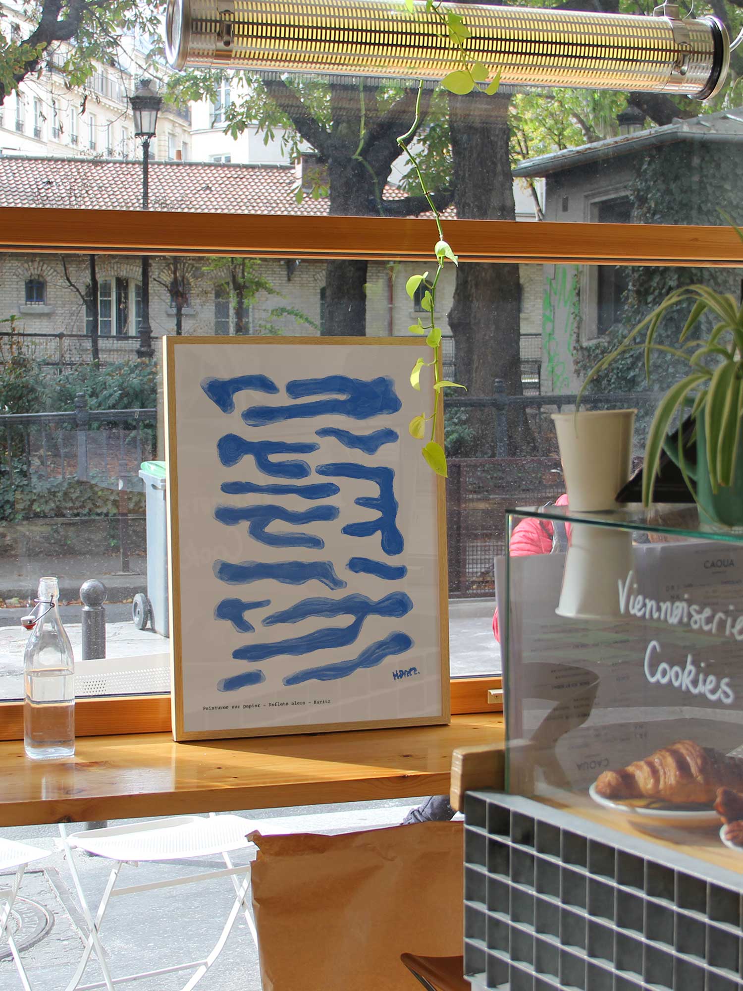 Affiche Reflets bleus de Haritz dans un coffee shop parisien lumineux et branché avec vue sur rue.