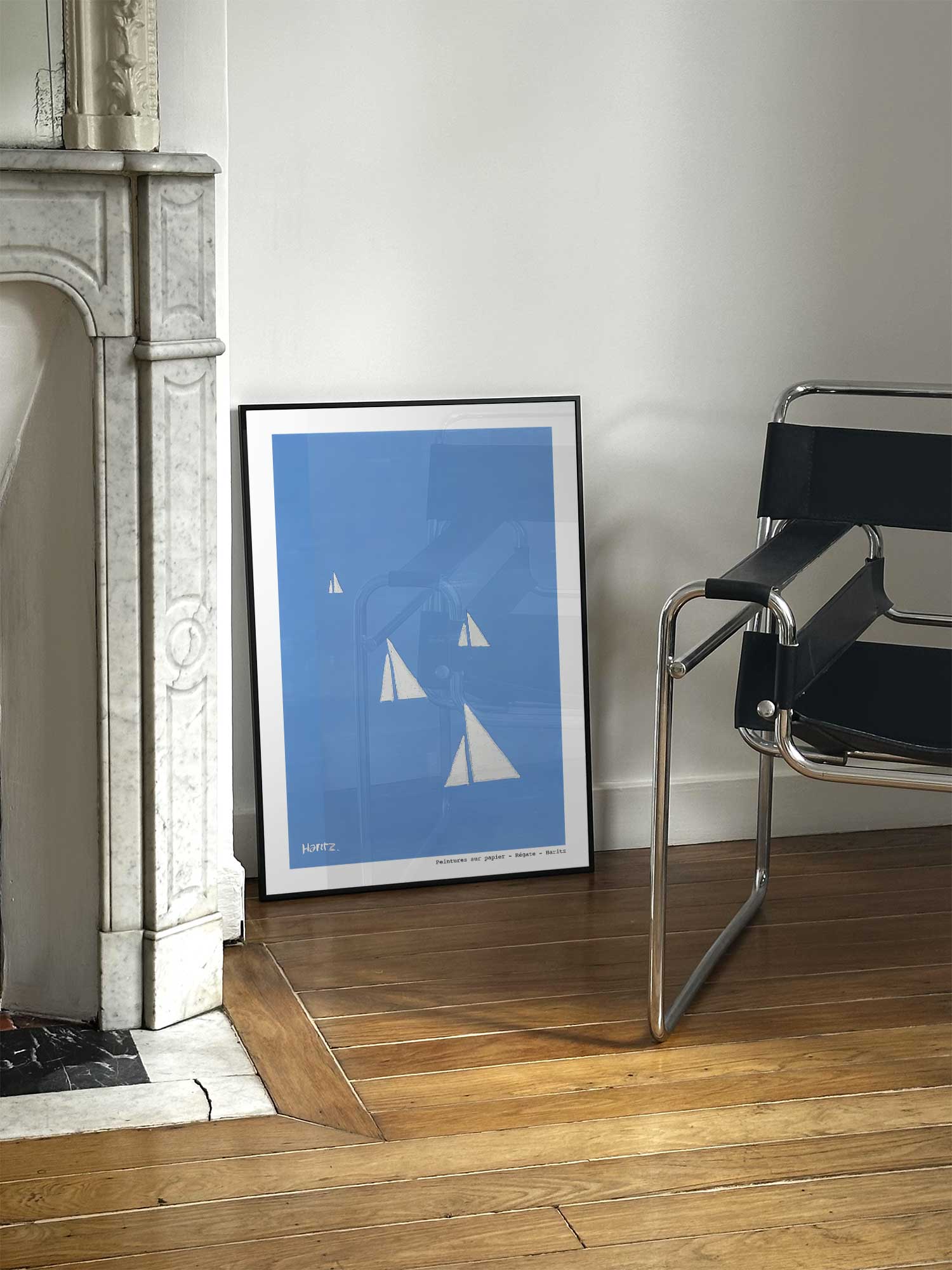 Affiche Régate de Haritz posée près d'une cheminée en marbre avec chaise design dans un salon d'appartement parisien.