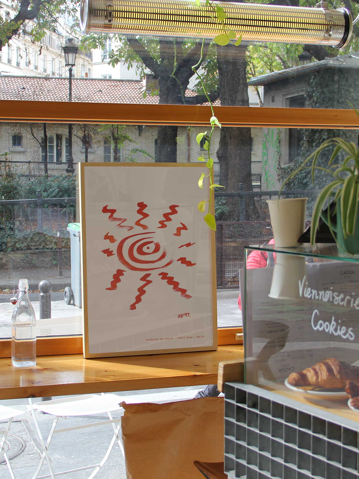 Affiche Soleil rouge de Haritz dans un coffee shop parisien lumineux et branché avec vue sur rue.