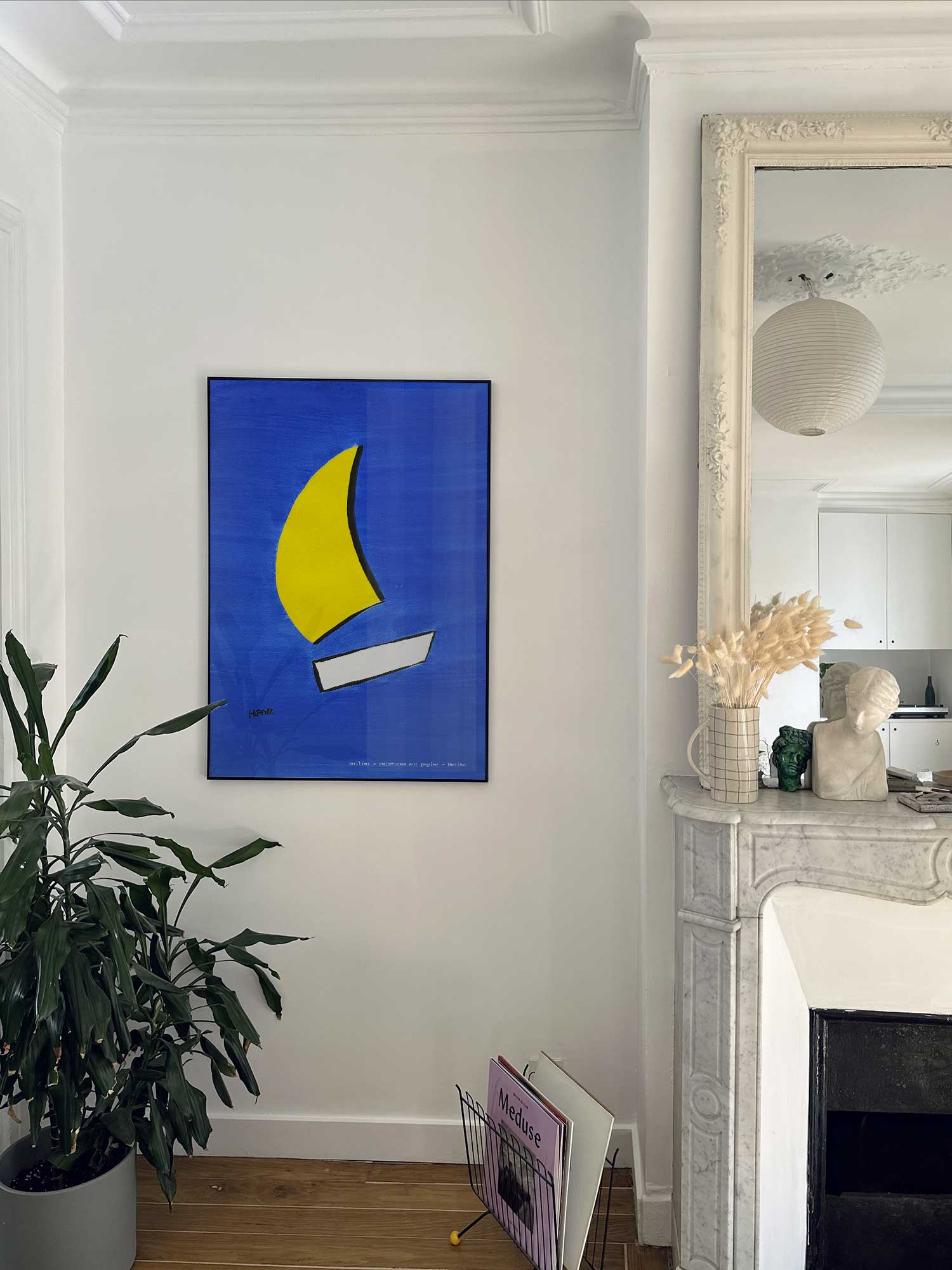 Affiche Voilier de Haritz accrochée au mur près d'une cheminée en marbre dans un appartement parisien.