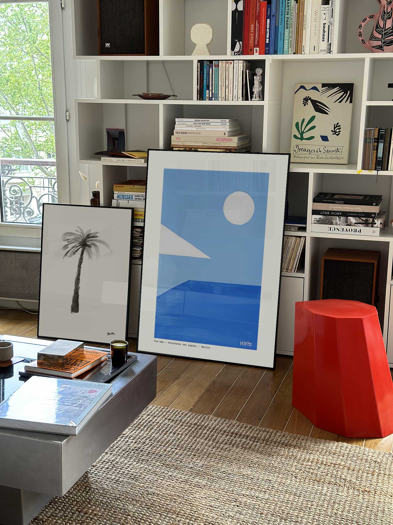 Affiche Vue mer de Haritz grand format dans un salon parisien design devant une bibliothèque blanche avec livres d'art.