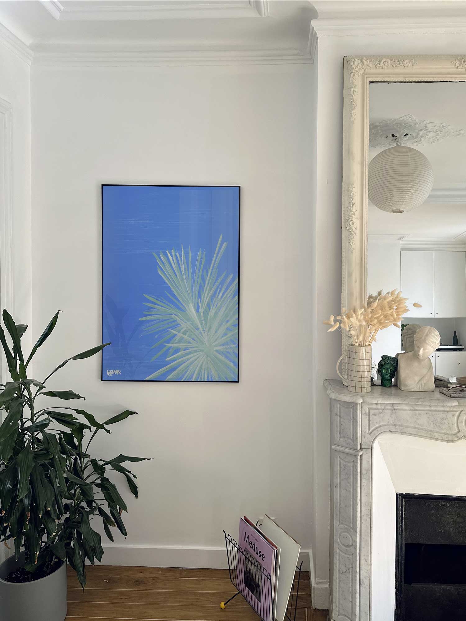 Affiche yucca de Haritz accrochée au mur près d'une cheminée en marbre dans un appartement parisien.
