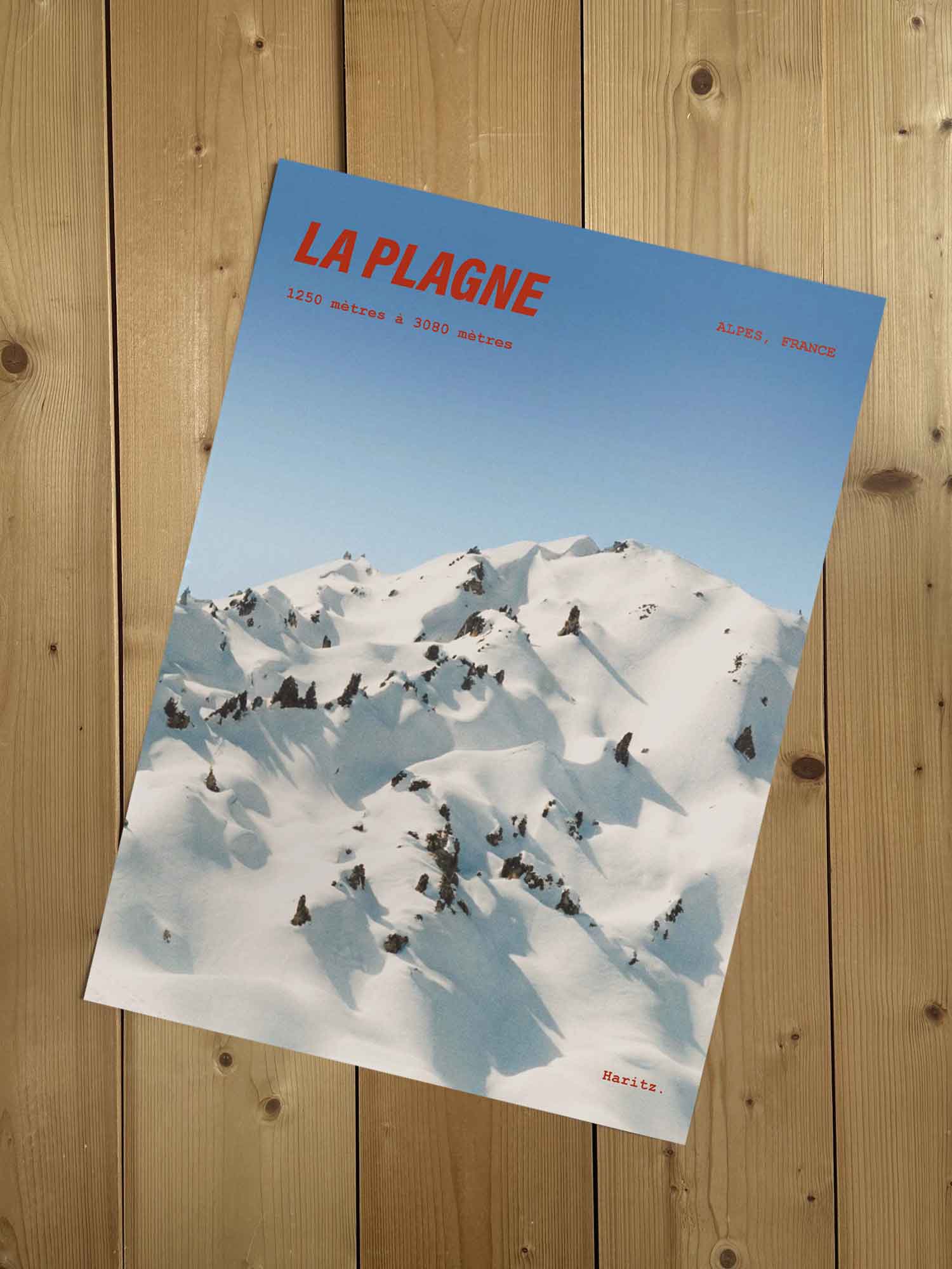 Affiche La Plagne vintage encadrée posée sur meuble en bois — sommets enneigés du domaine entre 1250 et 3080 mètres, photographie argentique Haritz