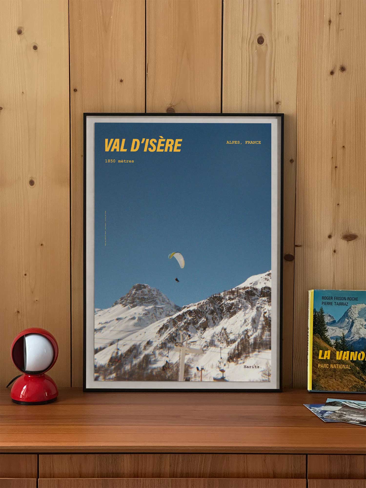 Affiche Val d'Isère vintage encadrée posée sur meuble en bois — parapente dans le ciel bleu à 1850 mètres, photographie argentique Haritz