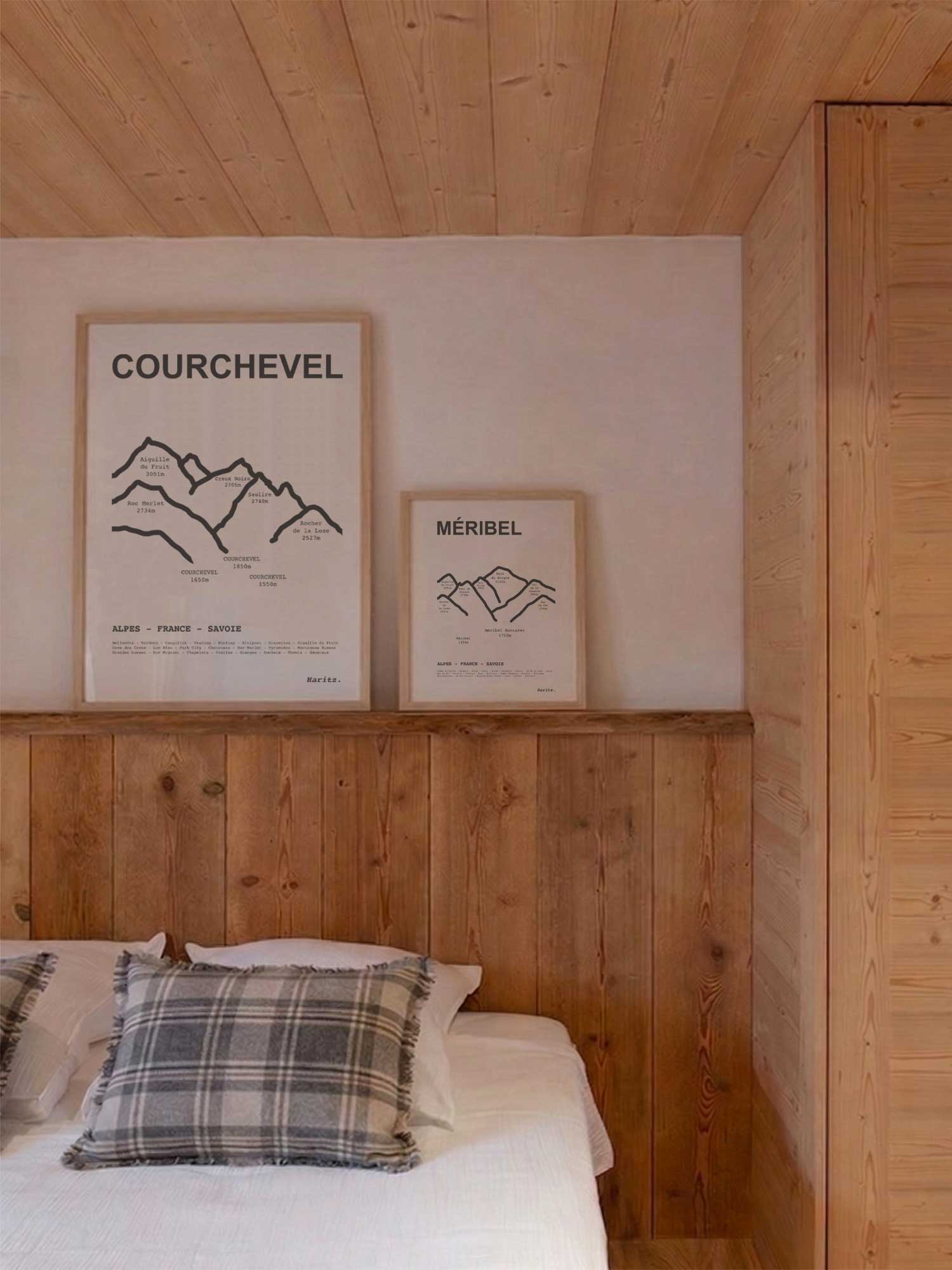 Affiches Courchevel et Méribel représentant les sommets des stations, encadrées posées au-dessus d’un lit dans une chambre de chalet de montagne, décoration murale alpine signée Haritz.