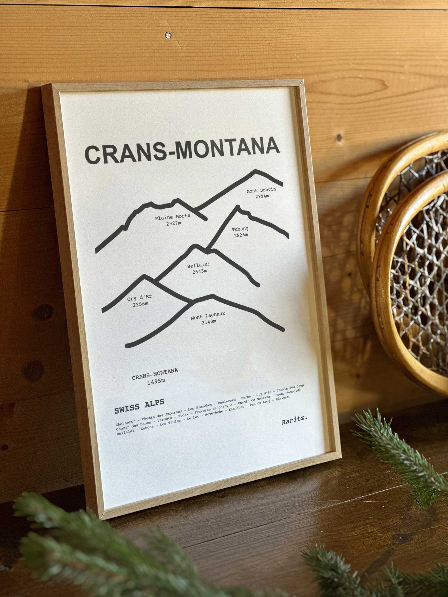 Affiche Crans-Montana du tracé topographique des sommets dans un cadre en bois naturel, mise en scène dans une décoration chalet avec objets vintage et raquettes à neige, par Haritz.
