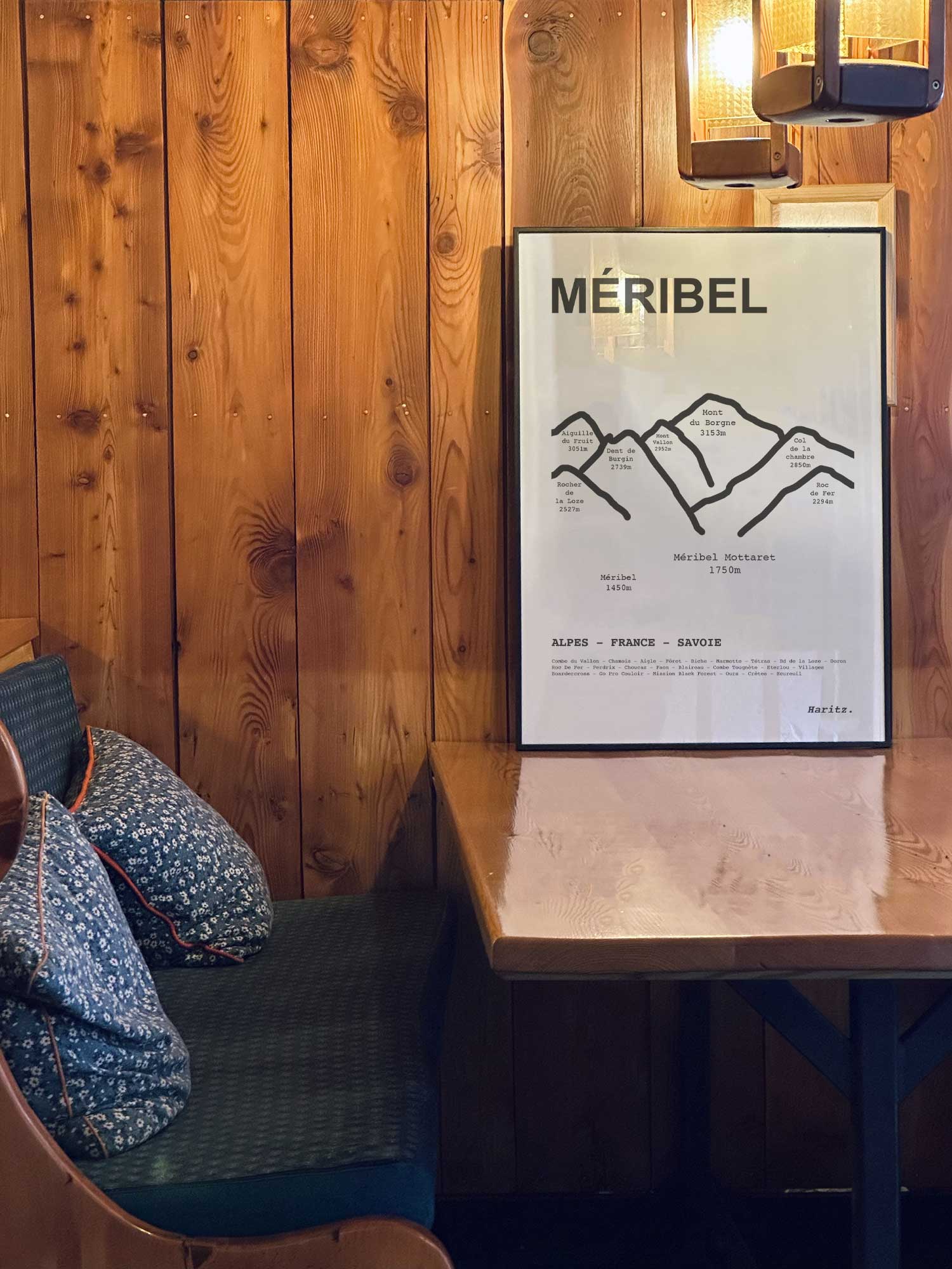 Affiche Méribel des sommets topographiques encadrée dans un restaurant de montagne en bois avec ambiance chalet chaleureuse, décoration murale signée Haritz.