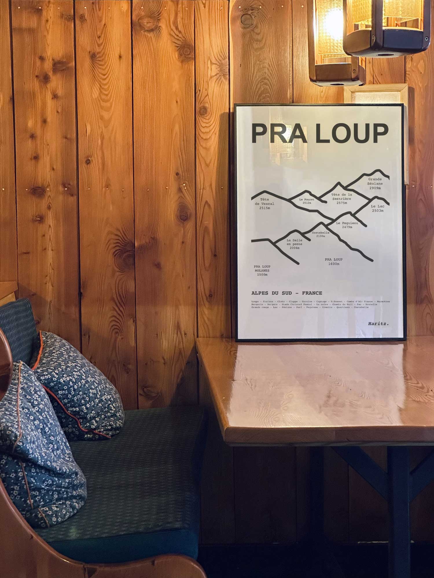 Affiche Pra Loup des sommets topographiques encadrée dans un restaurant de montagne en bois avec ambiance chalet chaleureuse, décoration murale signée Haritz.