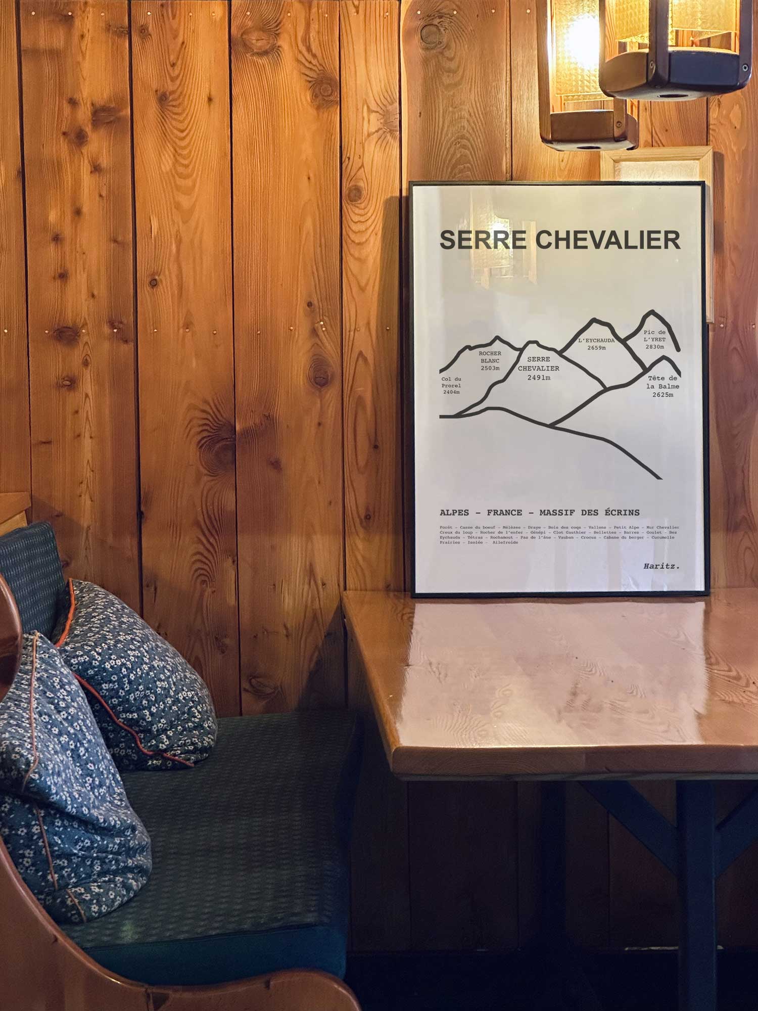 Affiche Serre Chevalier des sommets topographiques encadrée dans un restaurant de montagne en bois avec ambiance chalet chaleureuse, décoration murale signée Haritz.