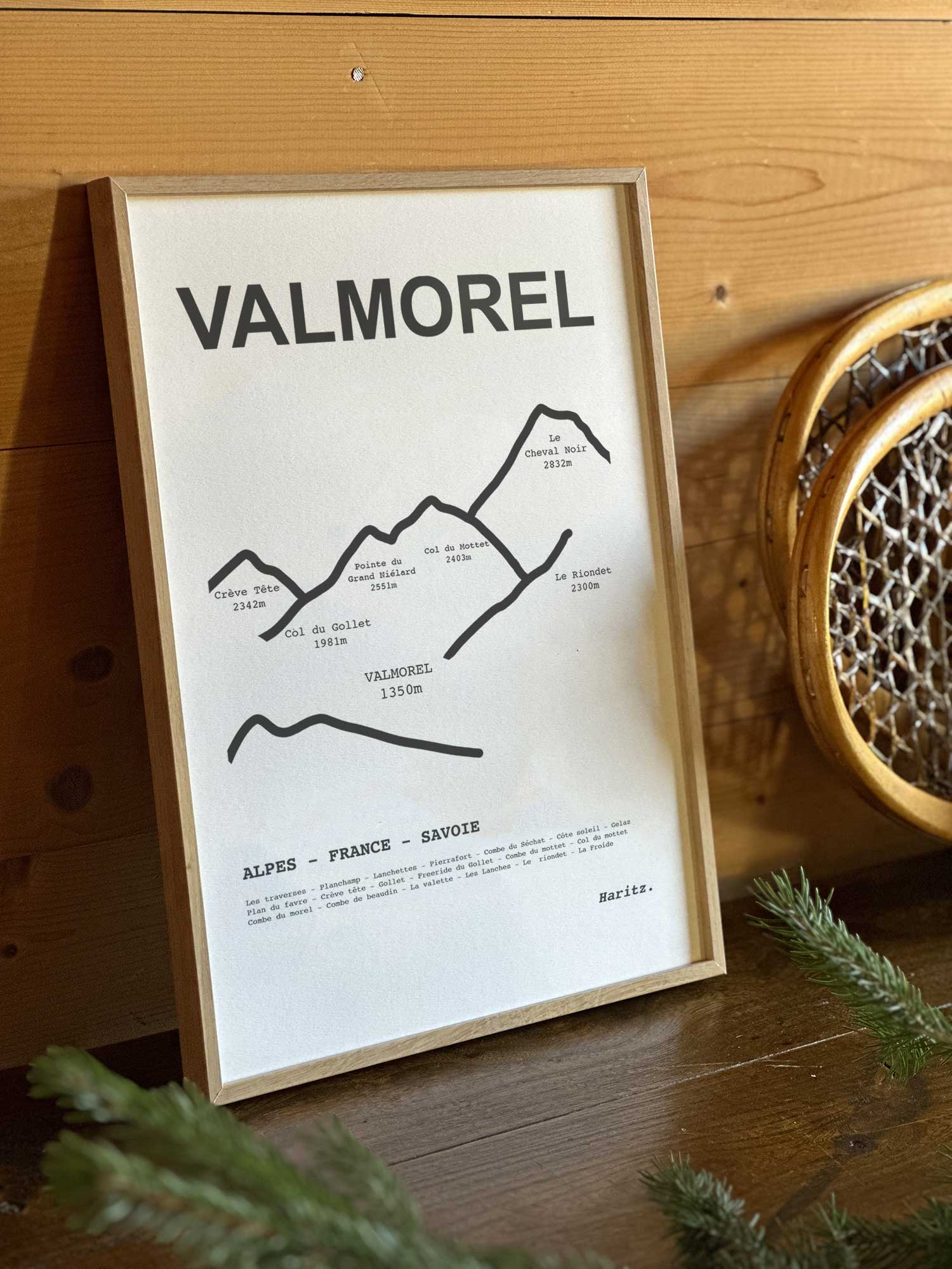 Affiche Valmorel du tracé topographique des sommets dans un cadre en bois naturel, mise en scène dans une décoration chalet avec objets vintage et raquettes à neige, par Haritz.