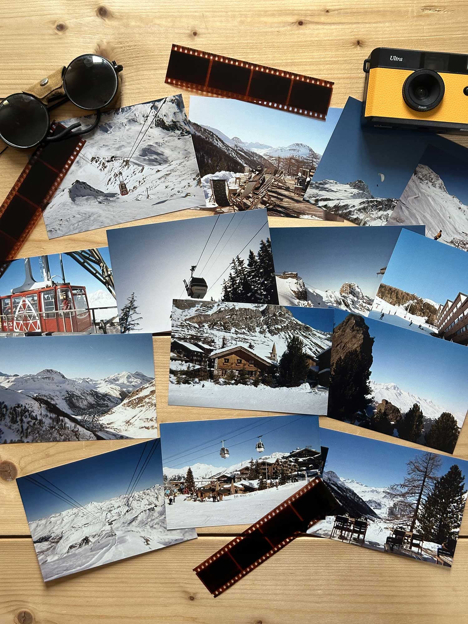Photographies argentiques Haritz des stations de ski en hiver, posées sur unetable en bois à côté d'un appareil photo argentique