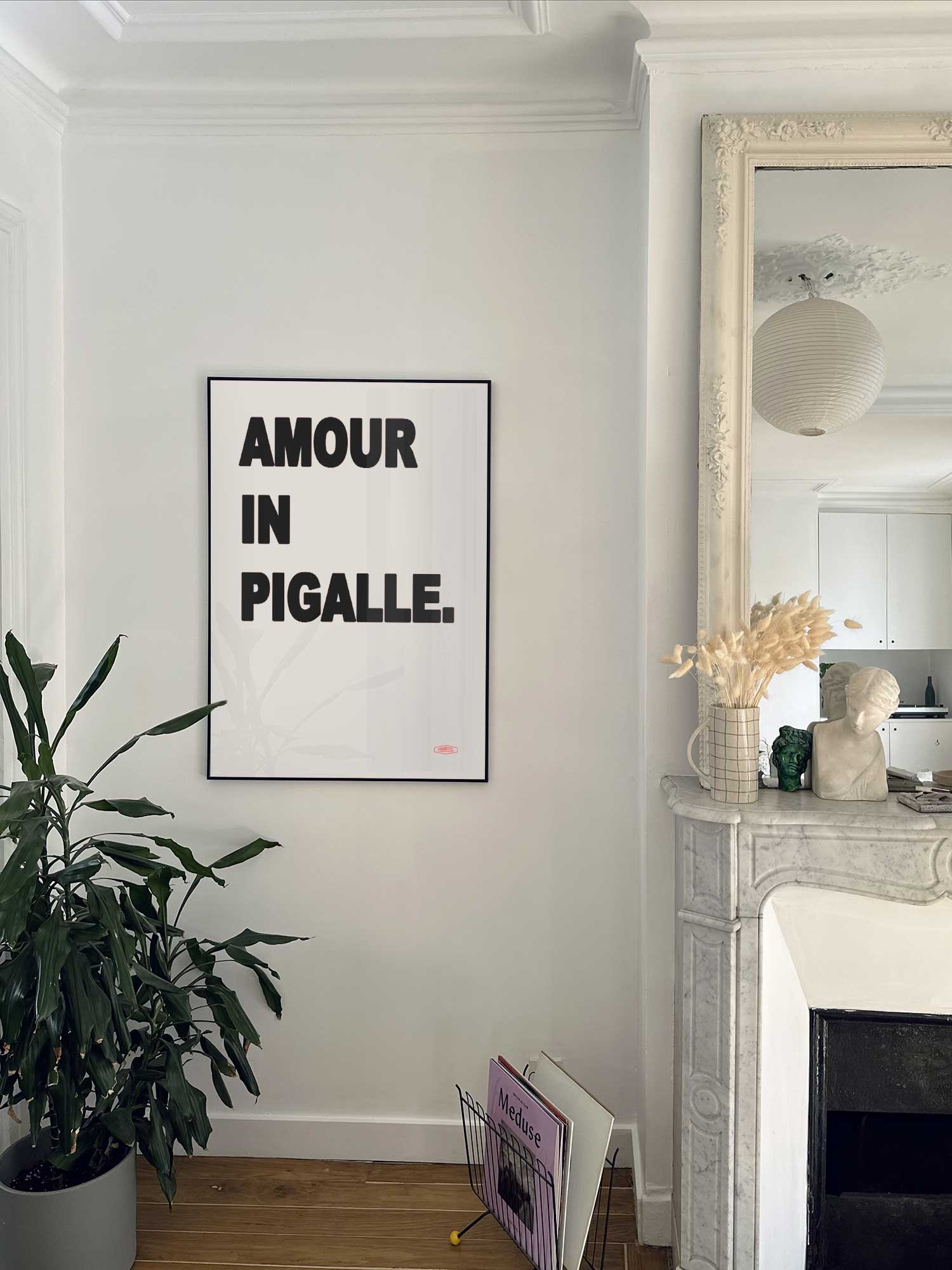 Affiche  Amour In Pigalle de Haritz accrochée au mur près d'une cheminée en marbre dans un appartement parisien.