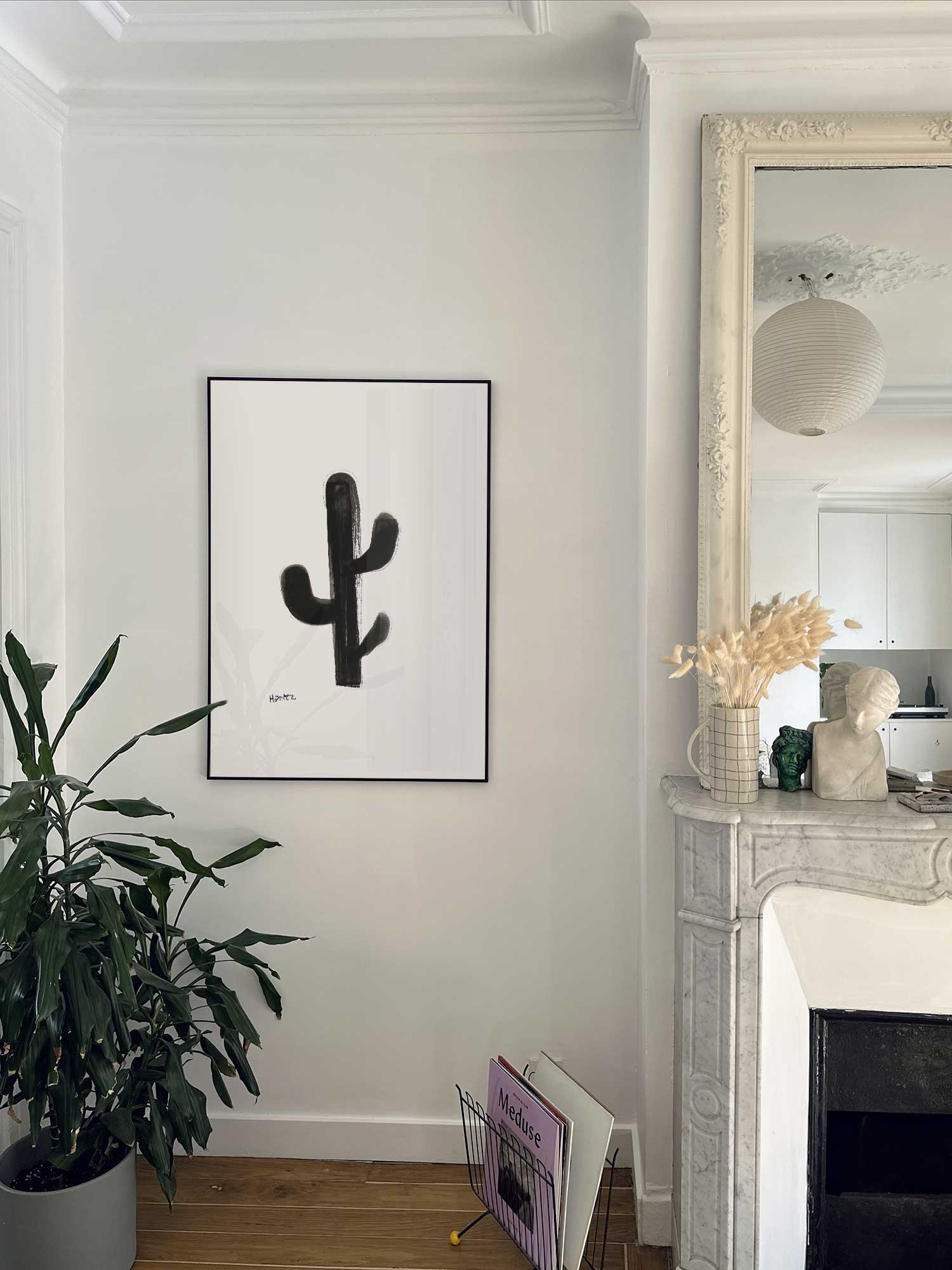 Affiche Cactus de Haritz accrochée au mur près d'une cheminée en marbre dans un appartement parisien.