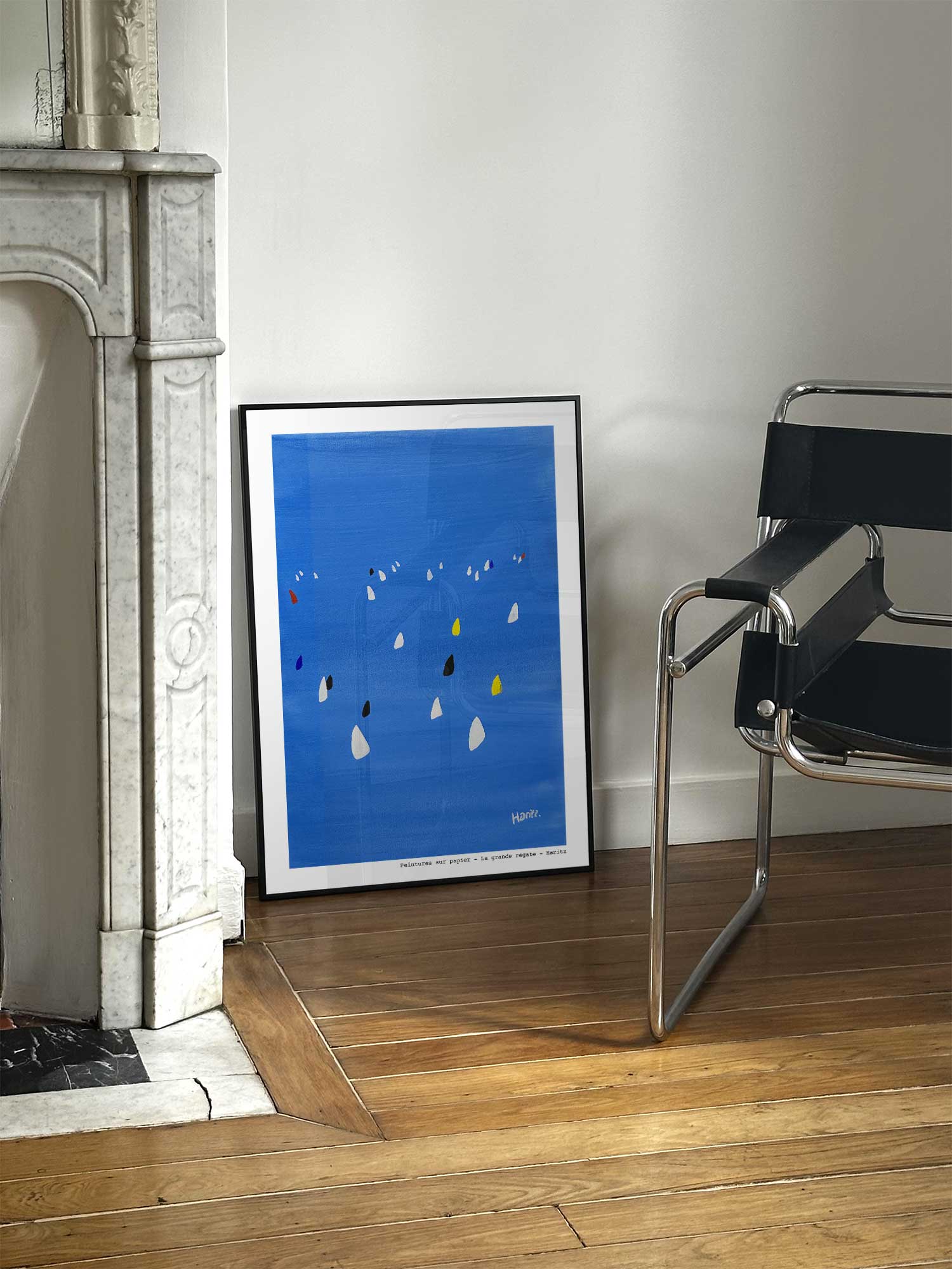 Affiche La grande régate de Haritz posée près d'une cheminée en marbre avec chaise design dans un salon d'appartement parisien.
