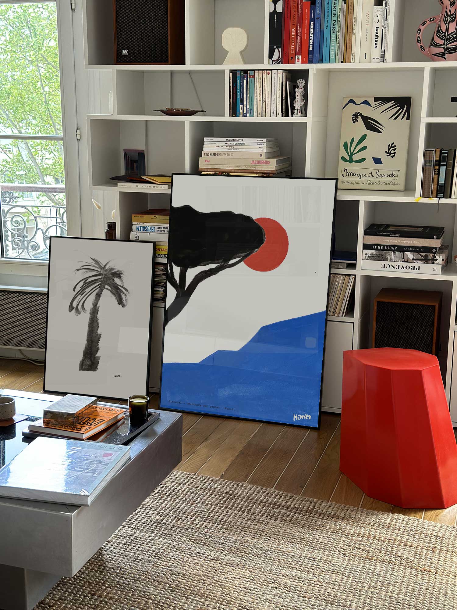 Affiche Littoral de Haritz grand format dans un salon parisien design devant une bibliothèque blanche avec livres d'art.