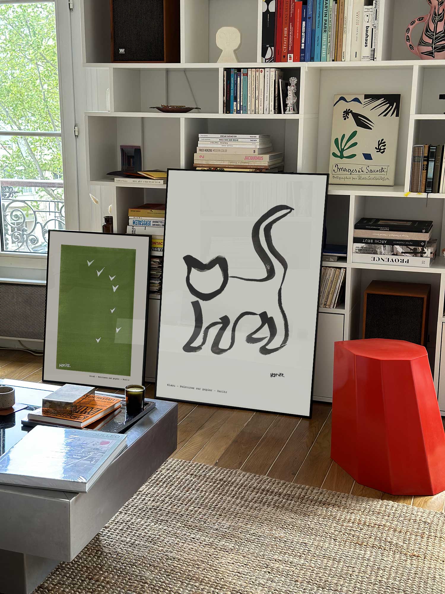 Affiche Miaou de Haritz grand format dans un salon parisien design devant une bibliothèque blanche avec livres d'art.
