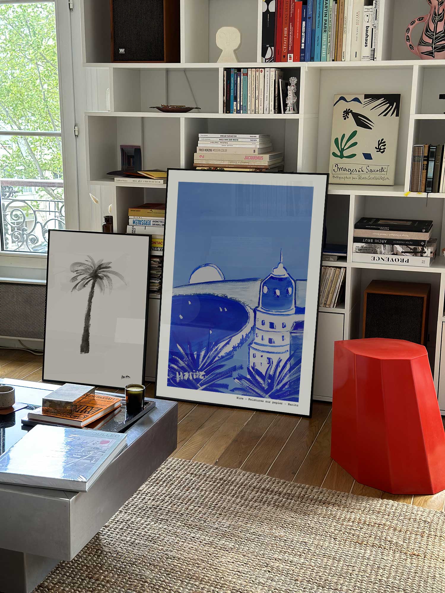 Affiche Nice de Haritz grand format dans un salon parisien design devant une bibliothèque blanche avec livres d'art.