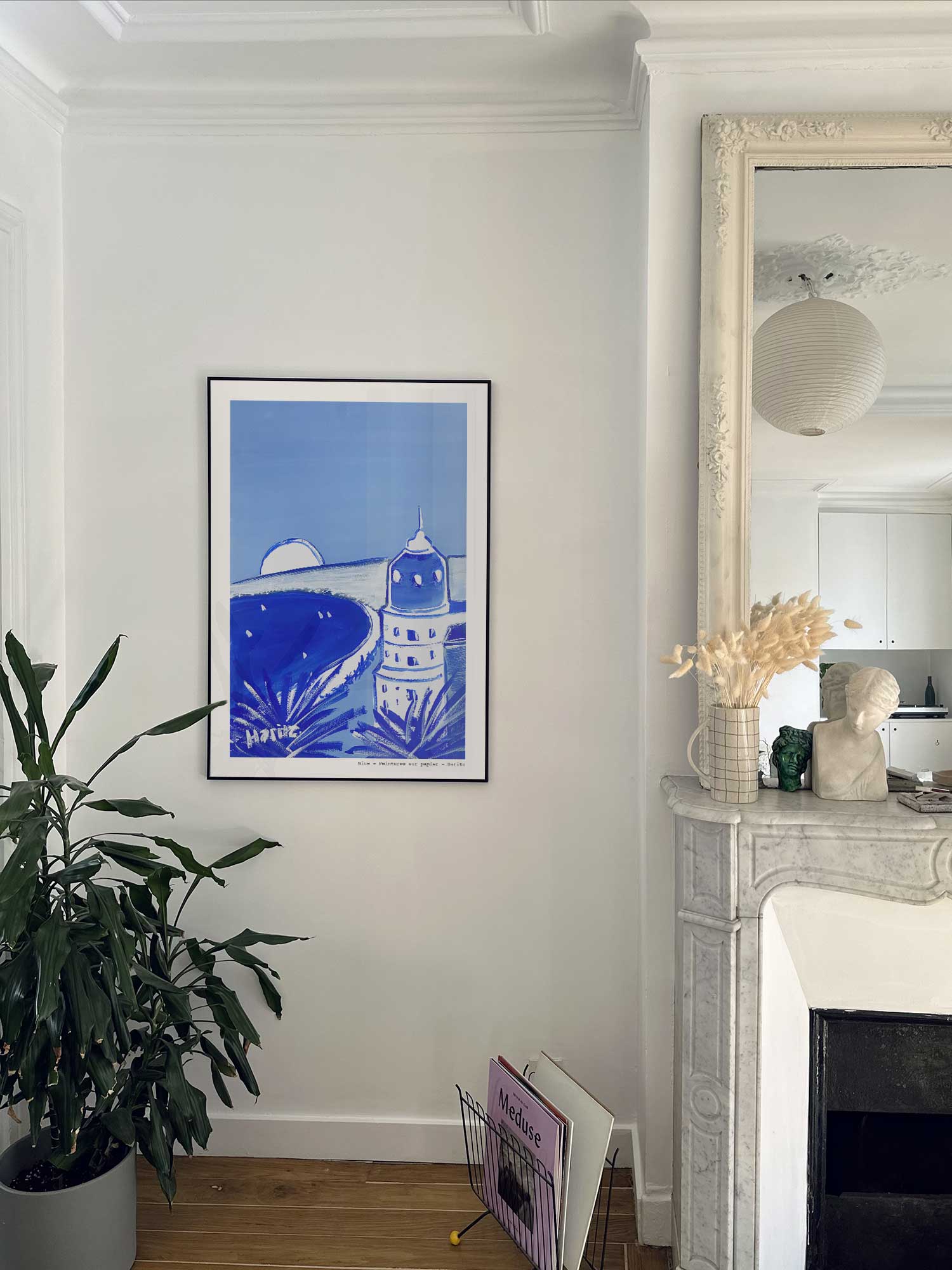 Affiche Nice de Haritz accrochée au mur près d'une cheminée en marbre dans un appartement parisien.