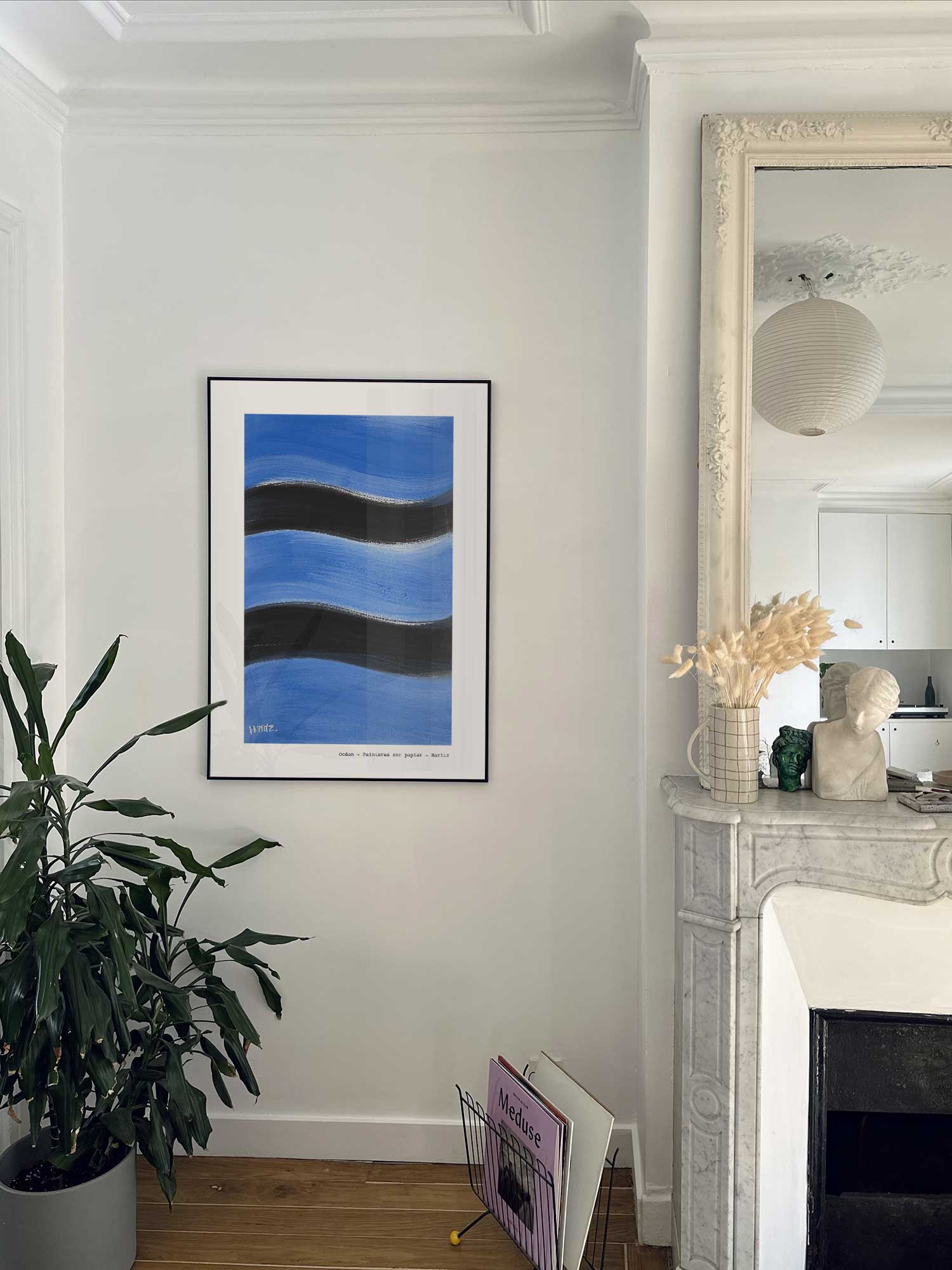 Affiche Océan de Haritz accrochée au mur près d'une cheminée en marbre dans un appartement parisien.