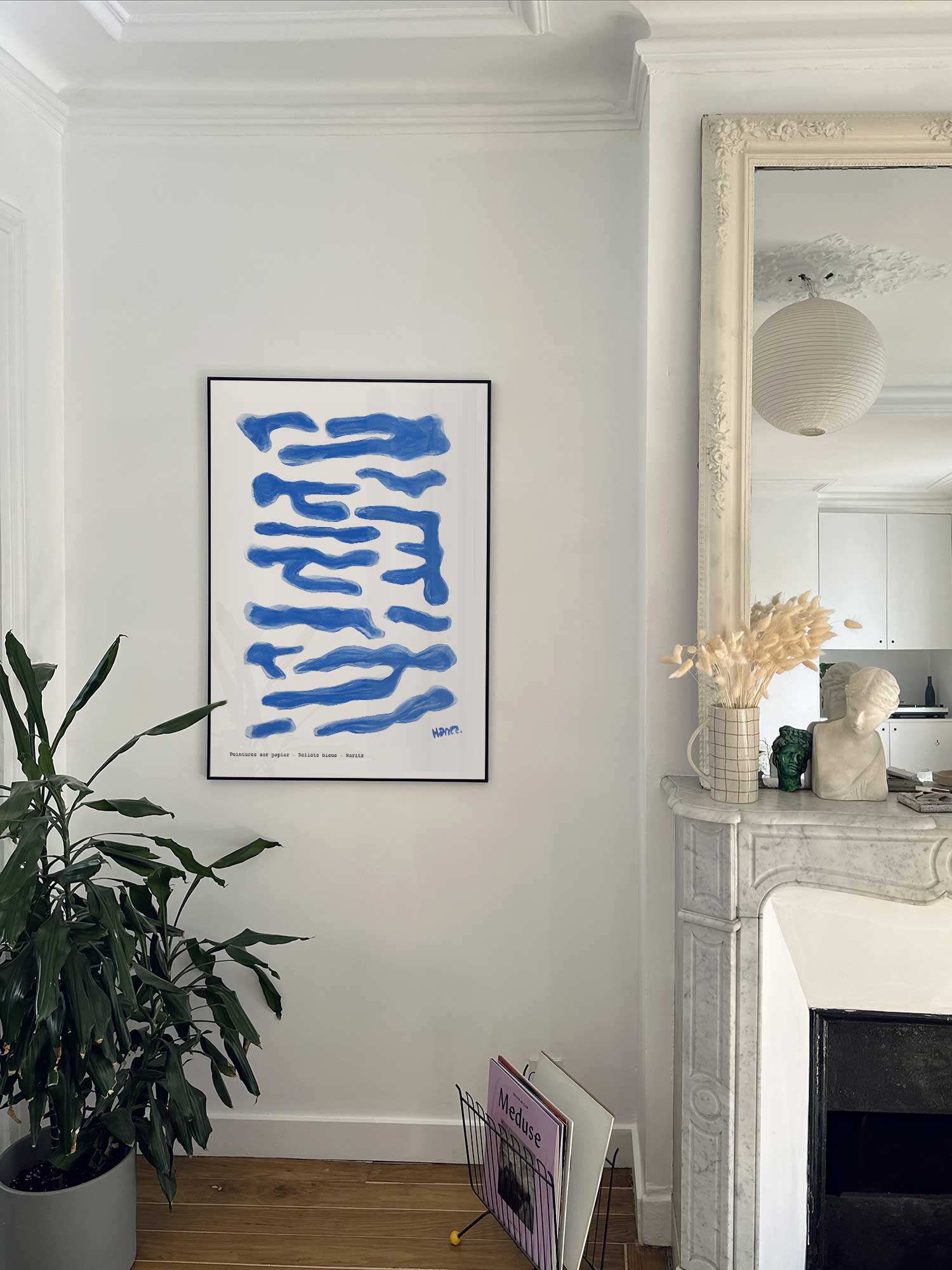 Affiche Reflets bleus de Haritz accrochée au mur près d'une cheminée en marbre dans un appartement parisien.