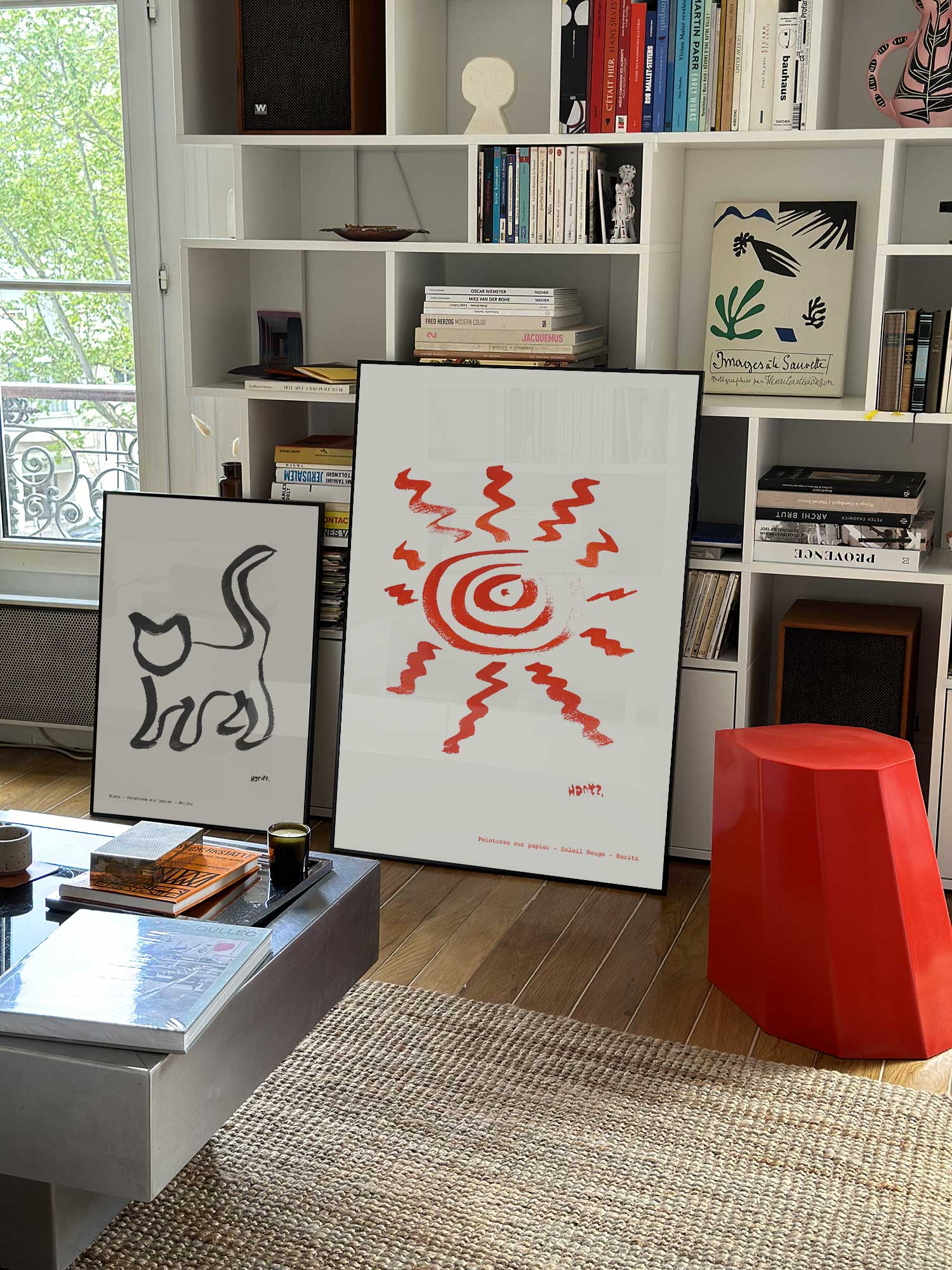 Affiche Soleil rouge de Haritz grand format dans un salon parisien design devant une bibliothèque blanche avec livres d'art.