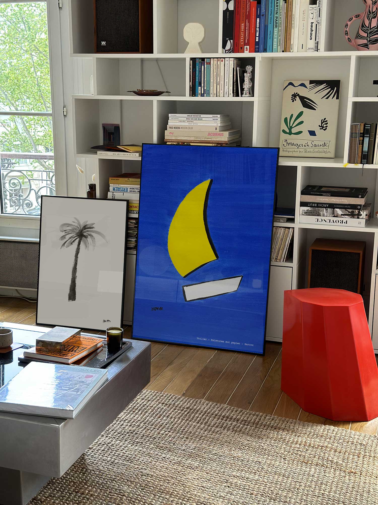 Affiche Voilier de Haritz grand format dans un salon parisien design devant une bibliothèque blanche avec livres d'art.