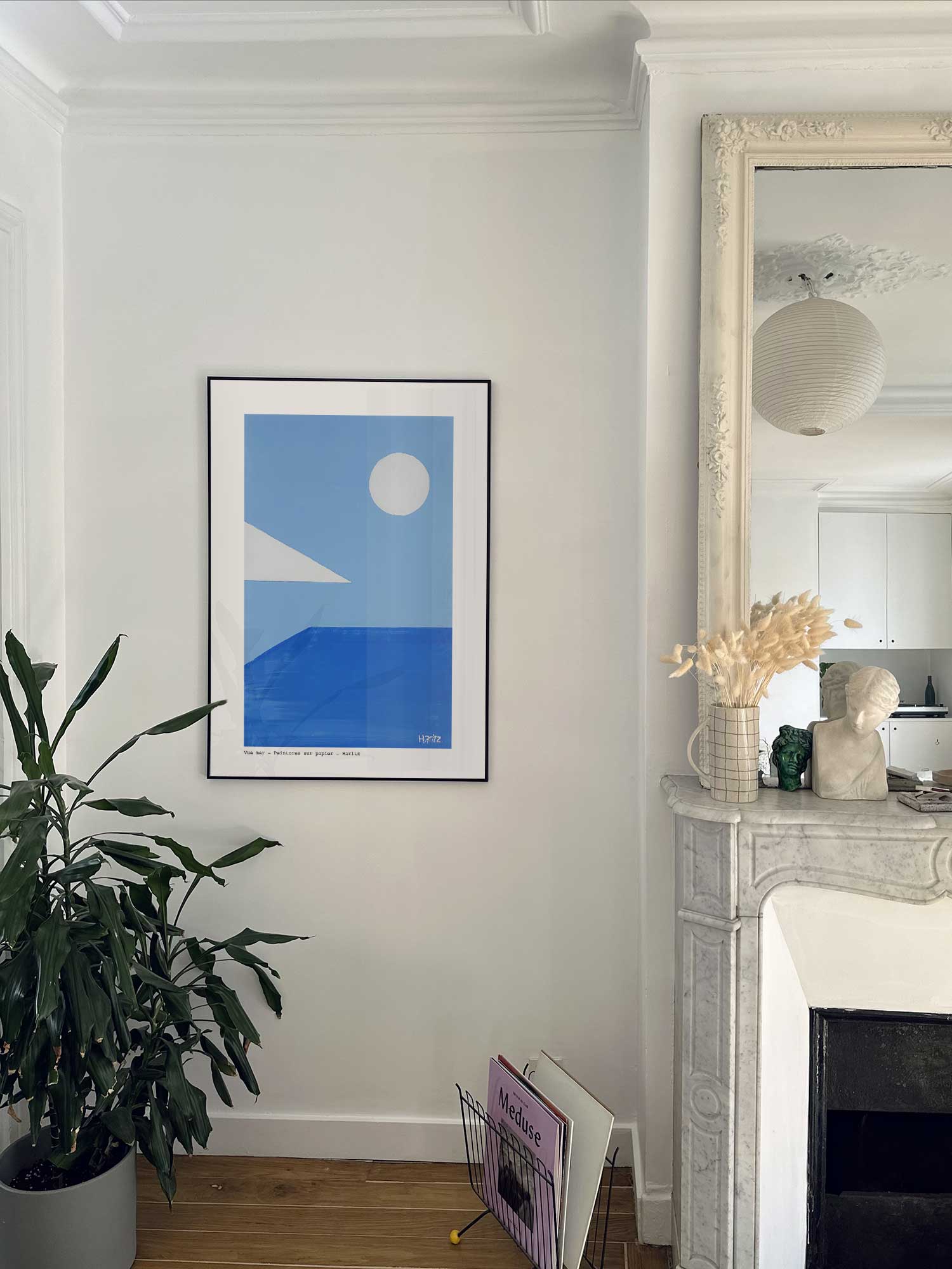 Affiche Vue mer de Haritz accrochée au mur près d'une cheminée en marbre dans un appartement parisien.