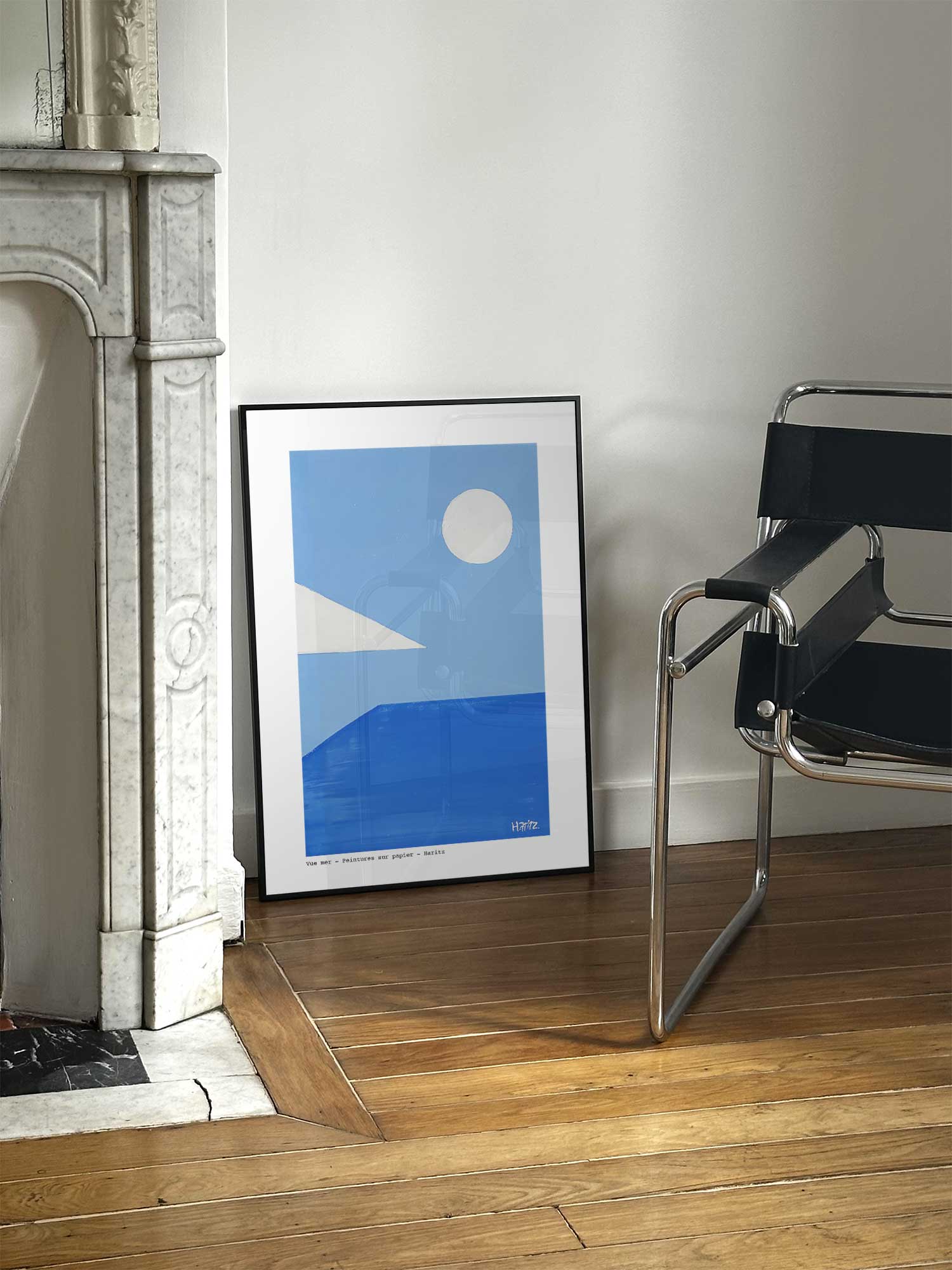 Affiche Vue mer de Haritz posée près d'une cheminée en marbre avec chaise design dans un salon d'appartement parisien.