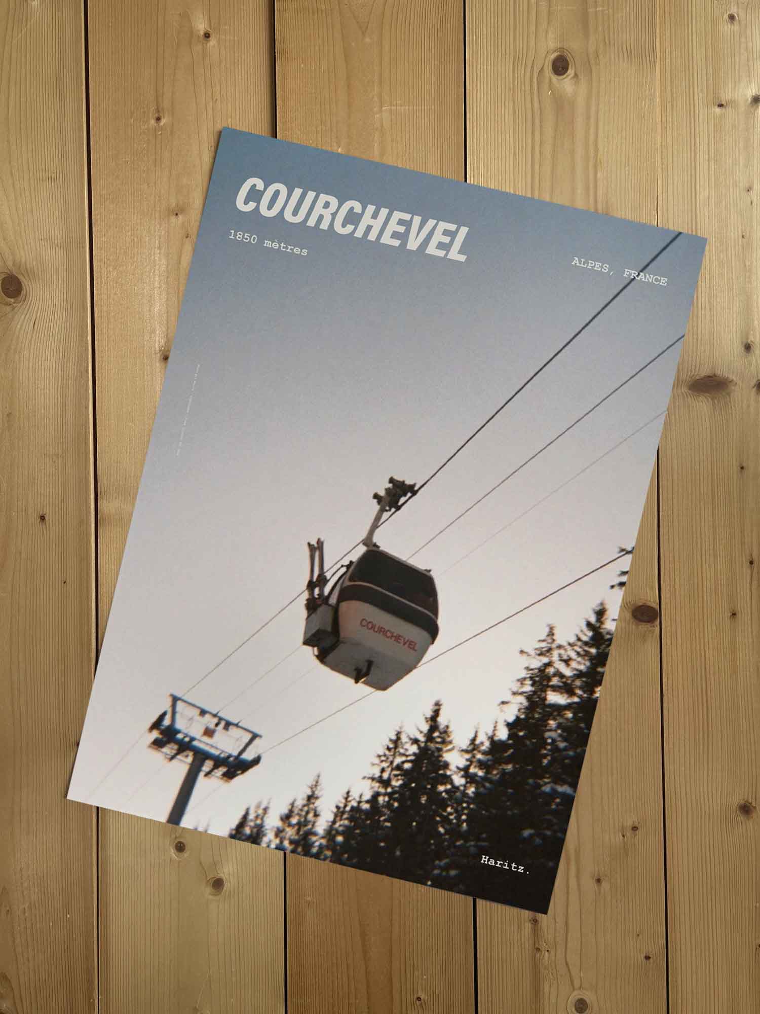 Affiche Courchevel vintage sans cadre posée sur parquet bois — télécabine 1850 mètres vue en contre-plongée, photographie argentique Haritz