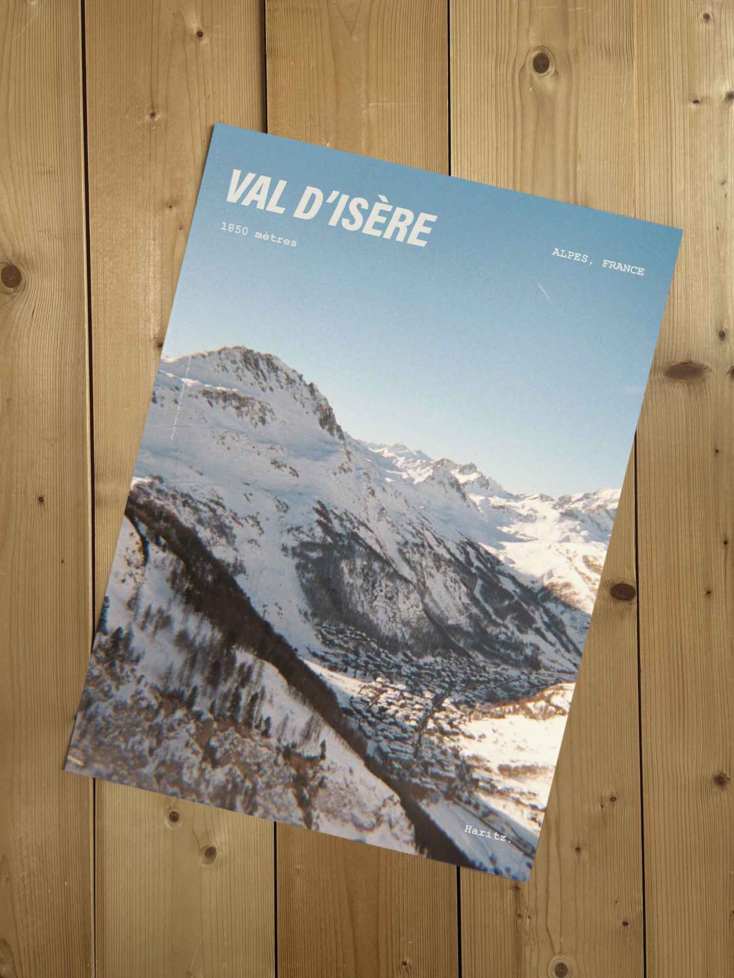 Affiche Val d'Isère vintage sans cadre posée sur parquet bois — vue plongeante sur le village dans la vallée, photographie argentique Haritz