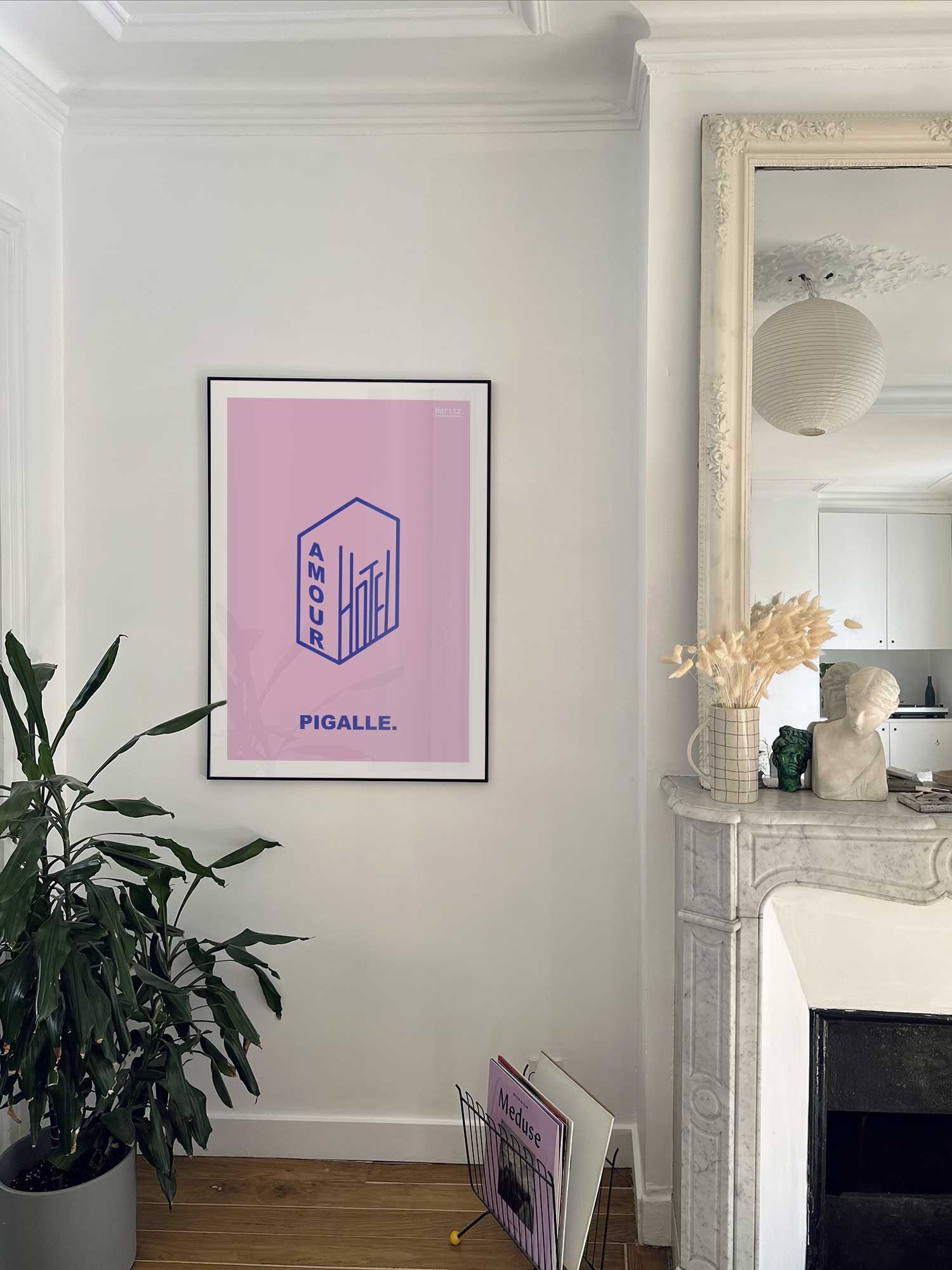 Affiche Hotel Amour de Haritz accrochée au mur près d'une cheminée en marbre dans un appartement parisien.