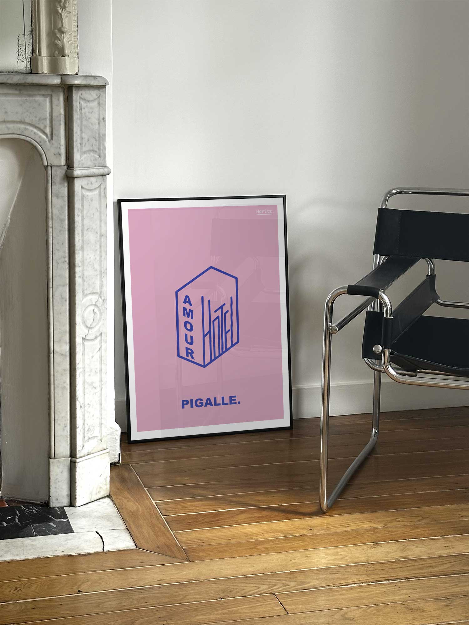 Affiche Hotel Amour de Haritz posée près d'une cheminée en marbre avec chaise design dans un salon d'appartement parisien.
