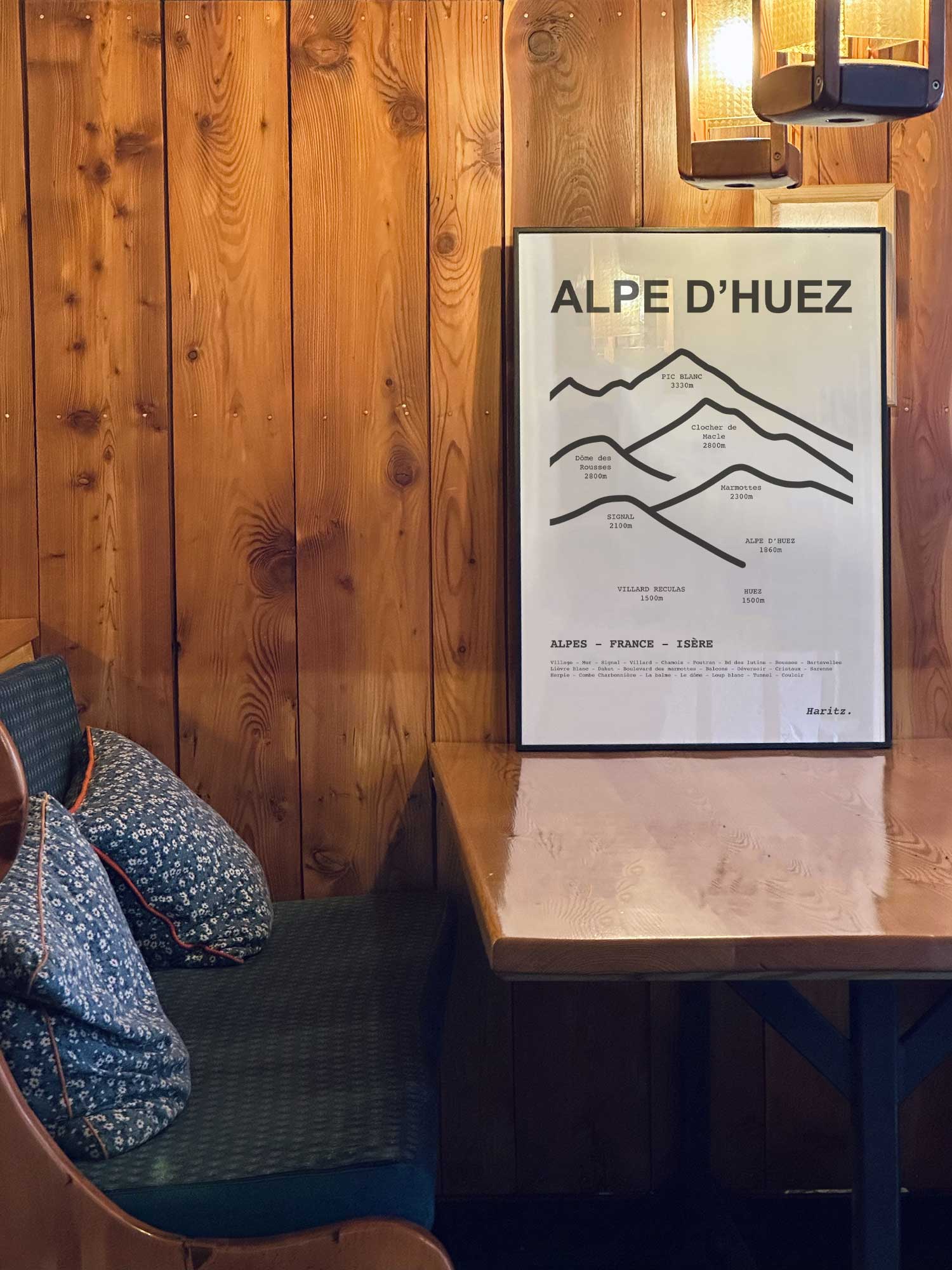 Affiche Alpe d'Huez des sommets topographiques encadrée dans un restaurant de montagne en bois avec ambiance chalet chaleureuse, décoration murale signée Haritz.