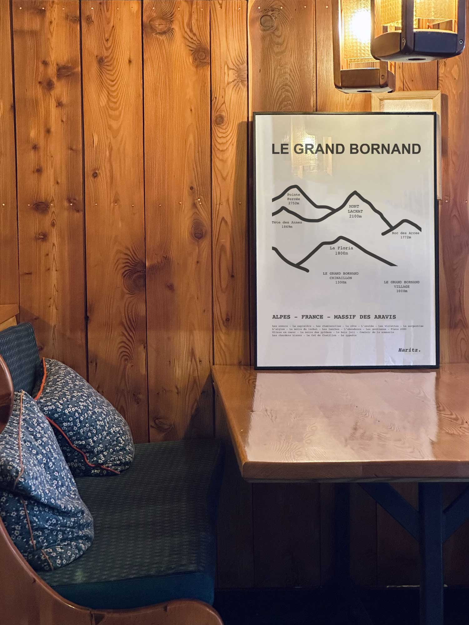 Affiche Le Grand Bornand des sommets topographiques encadrée dans un restaurant de montagne en bois avec ambiance chalet chaleureuse, décoration murale signée Haritz.