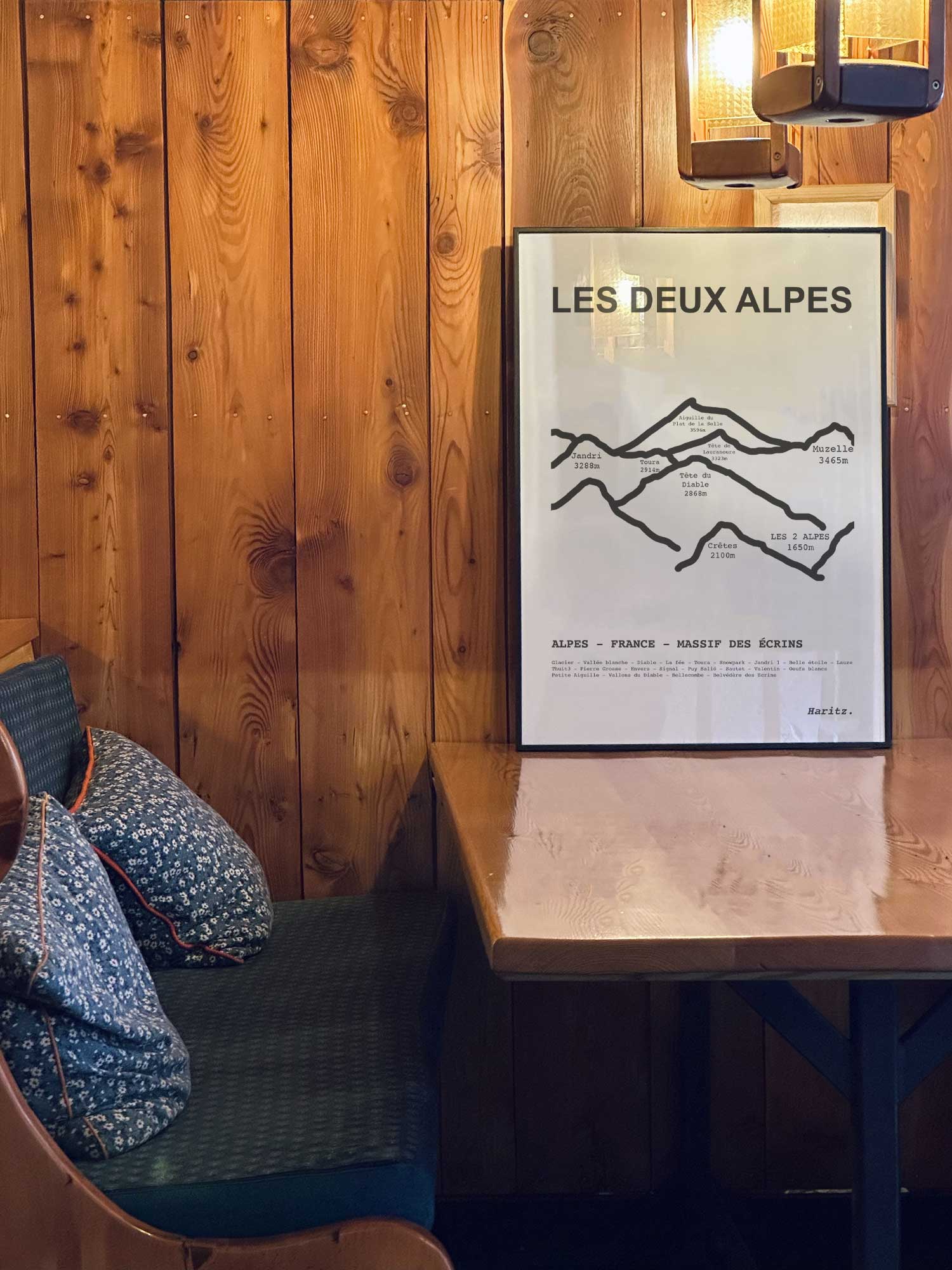 Affiche Les Deux Alpes des sommets topographiques encadrée dans un restaurant de montagne en bois avec ambiance chalet chaleureuse, décoration murale signée Haritz.