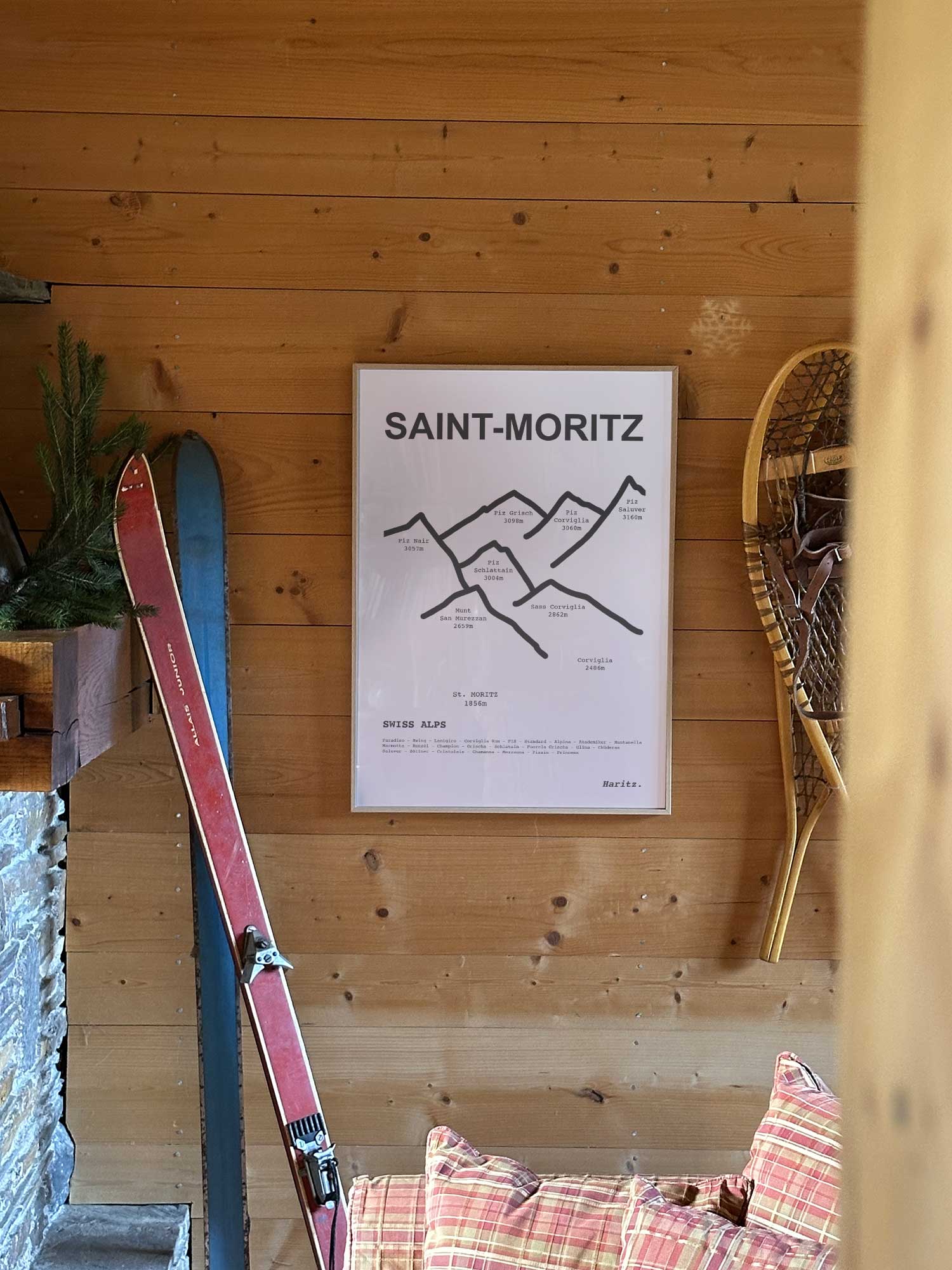 Affiche Saint-Moritz représentant les sommets de la station, accrochée au mur d’un salon de chalet avec skis vintage et raquettes à neige, décoration montagne Haritz.