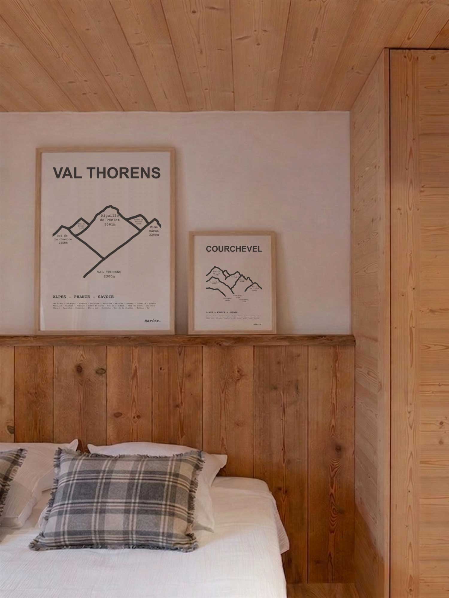 Affiches Val Thorens et Courchevel représentant les sommets des stations, encadrées posées au-dessus d’un lit dans une chambre de chalet de montagne moderne, décoration murale alpine signée Haritz.