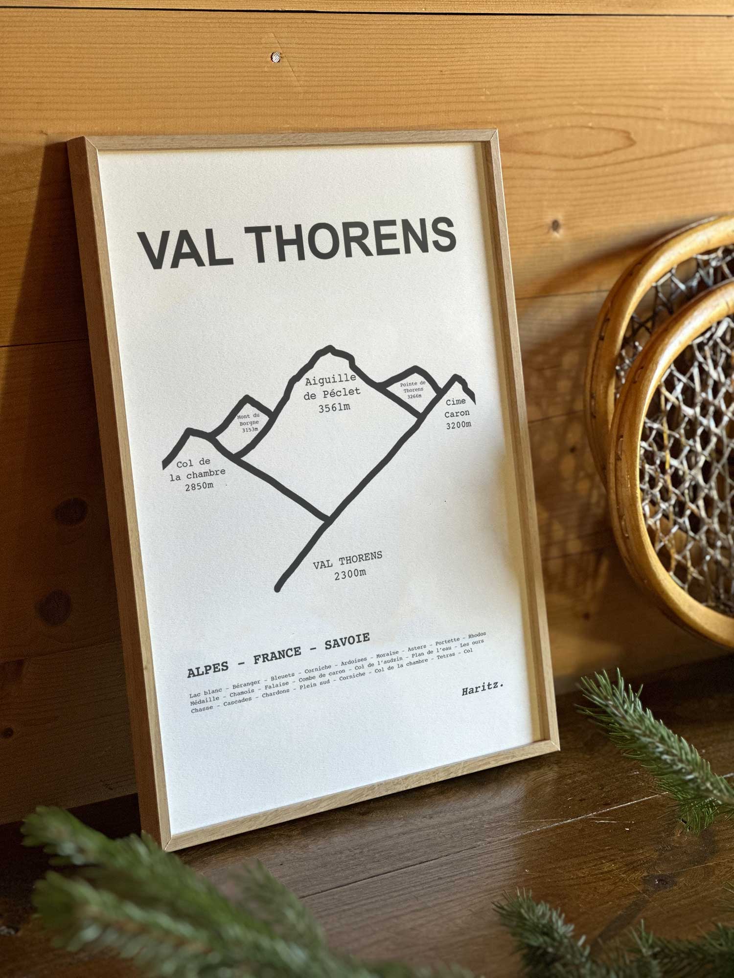 Affiche Val Thorens du tracé topographique des sommets dans un cadre en bois naturel, mise en scène dans une décoration chalet avec objets vintage et raquettes à neige, par Haritz.