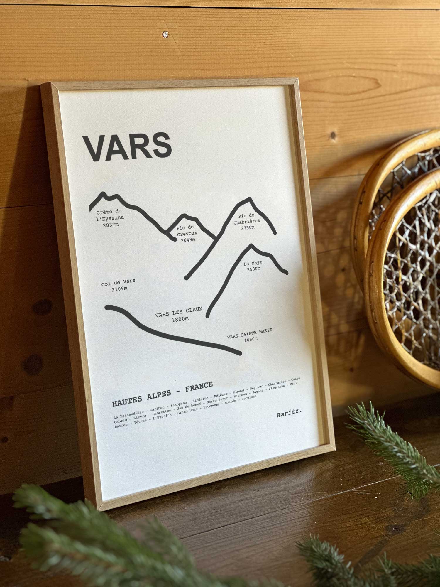 Affiche Vars du tracé topographique des sommets dans un cadre en bois naturel, mise en scène dans une décoration chalet avec objets vintage et raquettes à neige, par Haritz.